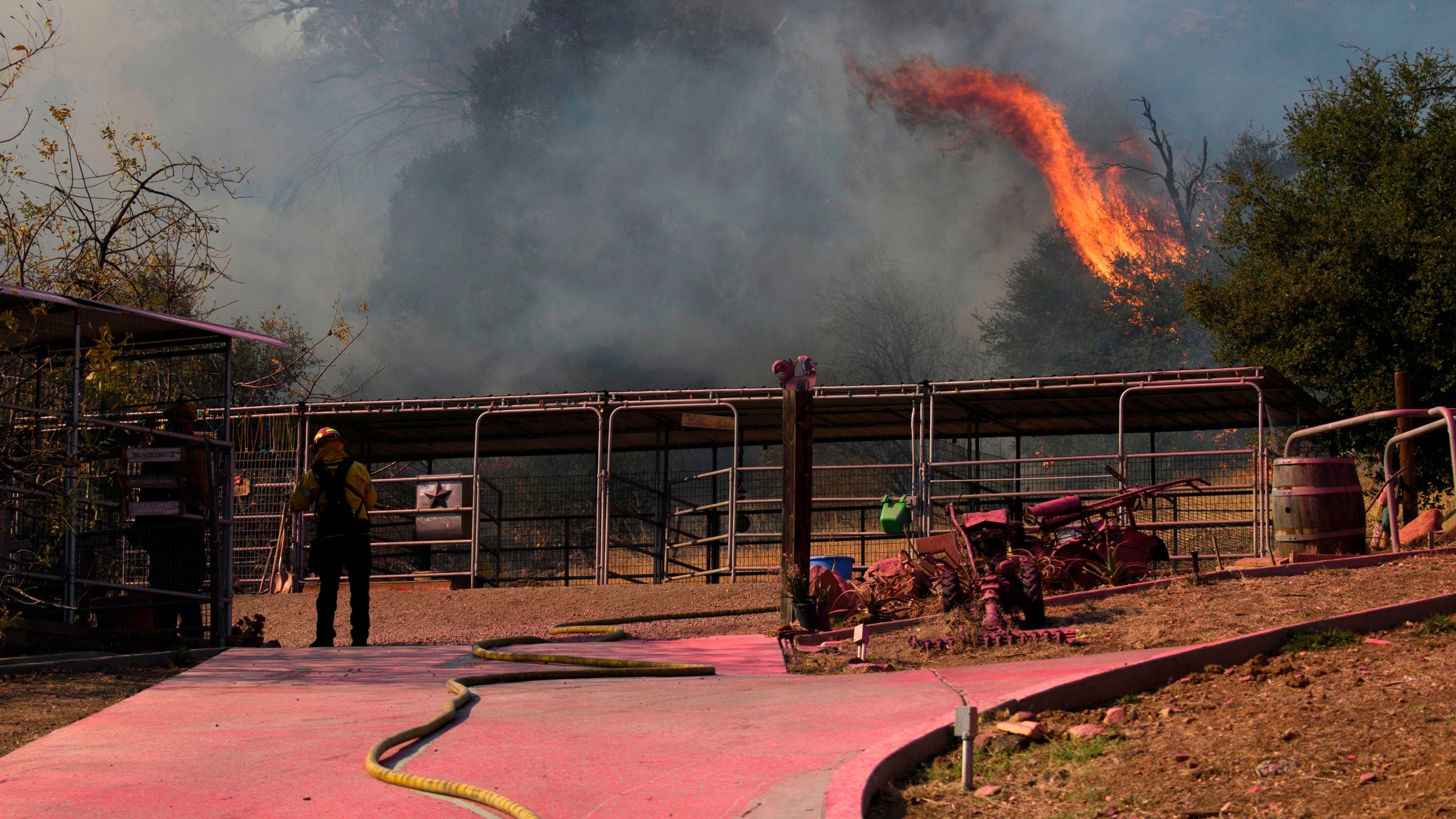 An Orange County Fire Authority firefighter stands on a driveway covered in fire retardant while working to contain the Bond Fire in Modjeska Canyon near Lake Forest on Dec. 3, 2020. (PATRICK T. FALLON/AFP via Getty Images)