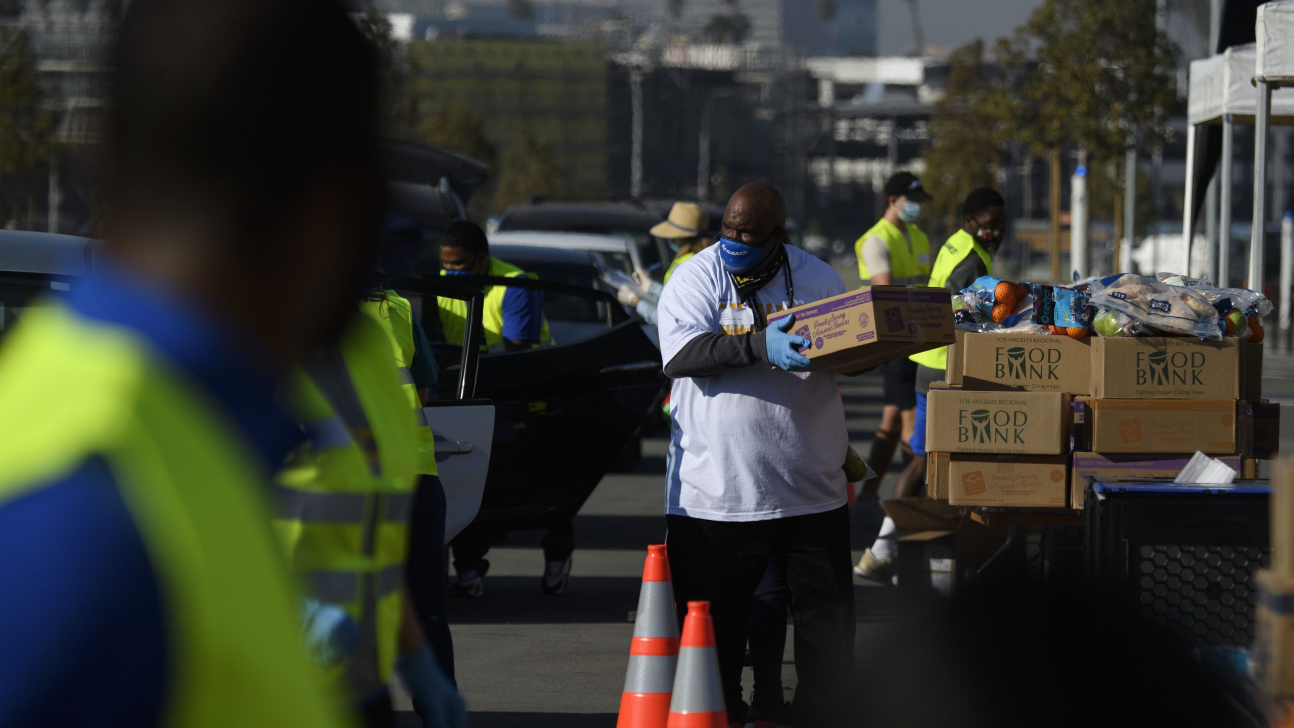 Volunteers load boxes of groceries into vehicles during a holiday mobile food distribution from the Los Angeles Regional Food Bank supported by the Los Angeles Rams NFL football team and Pechanga Resort Casino outside of SoFi Stadium on Dec. 22, 2020 in Inglewood. (PATRICK T. FALLON/AFP via Getty Images)