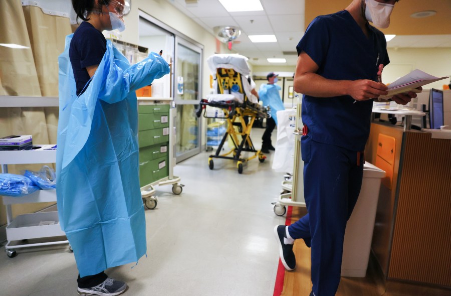 A clinician dons PPE (personal protective equipment) as she prepares to enter a patient's room in the emergency room at Sharp Memorial Hospital on December 15, 2020 in San Diego, California. (Mario Tama/Getty Images)