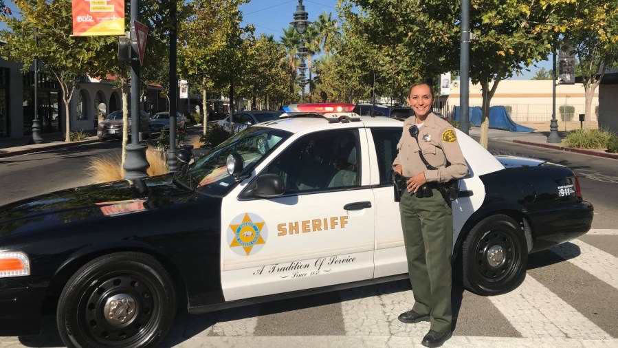 An L.A. County sheriff's deputy and patrol vehicle are seen in a photo from the Lancaster Sheriff's Station's Facebook page.