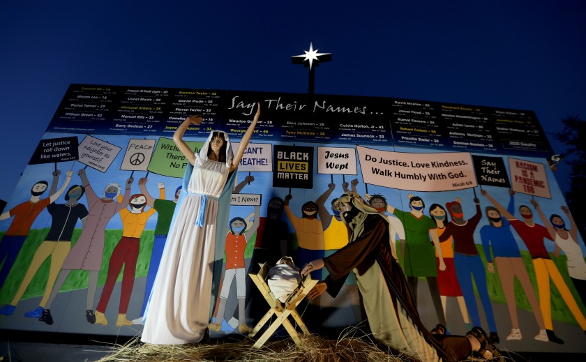 Claremont United Methodist Church put up a Nativity scene in December 2020 that shows Mary, Joseph and baby Jesus in front of a wall of people wearing masks and carrying signs that read “Black Lives Matter,” “I can’t breathe” and “Jesus wept,” along with Bible verses. (Luis Sinco/Los Angeles Times)