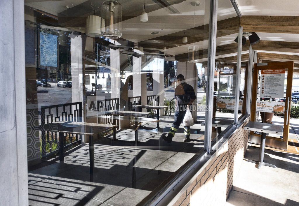 A take out customer is reflected in the window of Sharky's Woodfired Mexican Grill in the Sherman Oaks section of Los Angeles on Sunday Dec. 6, 2020. (AP Photo/Richard Vogel)