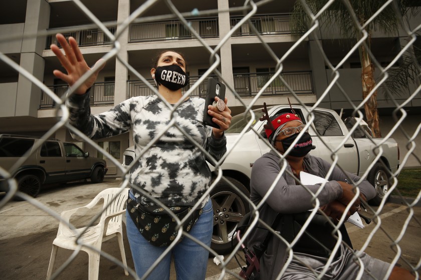 Genevieve Marilyn Green, a mother of three, livestreams video with her phone as Mikki Morris talks from inside of fencing that contains homeless people who are staying in the Studio 6 motel in Commerce. The motel residents were locked out of their roomsg.(Al Seib / Los Angeles Times)