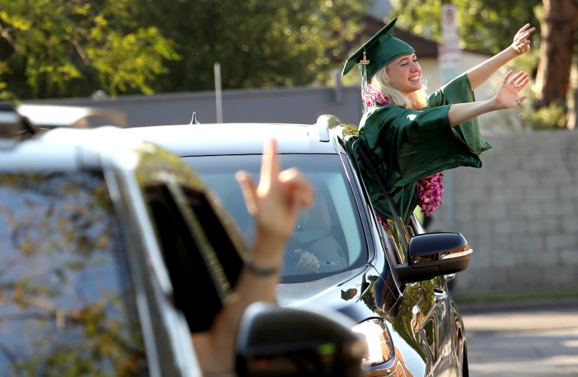 Naomi Shacham waves to her teachers during a drive-up graduation ceremony for the Class of 2020 at the New West Charter School in Los Angeles in June, 2020. (Genaro Molina / Los Angeles Times)