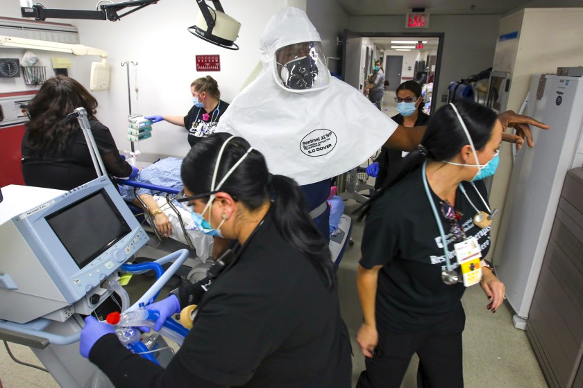 Dr. Leroy Pascal, in white protective gear, and emergency room nurses scramble to attend to a COVID-19 patient at Desert Valley Hospital on Thursday in Victorville.(Irfan Khan/Los Angeles Times)