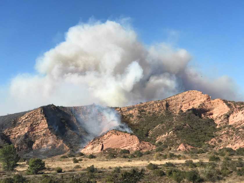 A large plume of smoke from the Bond Fire rises in the hills above Santiago Canyon Road in Orange County on Dec. 3, 2020. (Allen J. Schaben/Los Angeles Times)