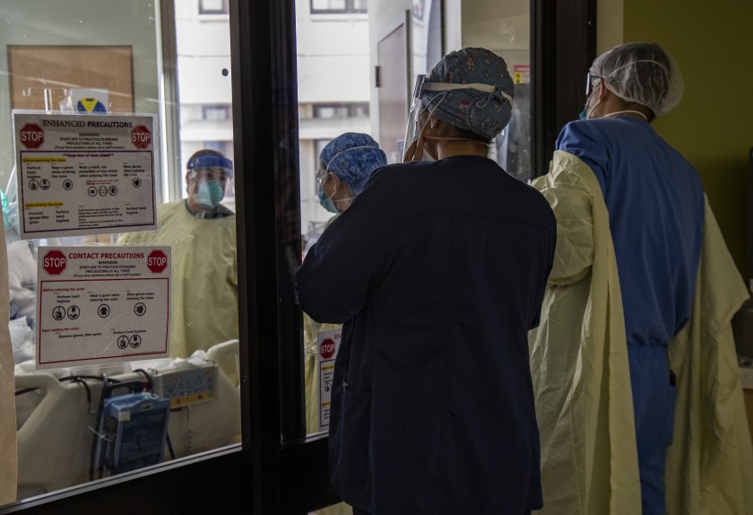 Pulmonologist Dr. Laren Tan, right, and his medical team of nurses and respiratory therapists look in on a COVID-19 patient before she is intubated in the ICU at Loma Linda University Medical Center on Dec. 15.(Gina Ferazzi/Los Angeles Times)