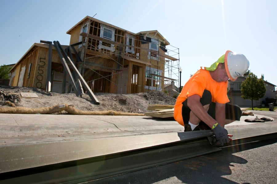 In this photo taken Aug. 16, 2017, sheet metal worker Benjamin Voget prepares to install a gutter on a home under construction in Sacramento. (Rich Pedroncelli / Associated Press)