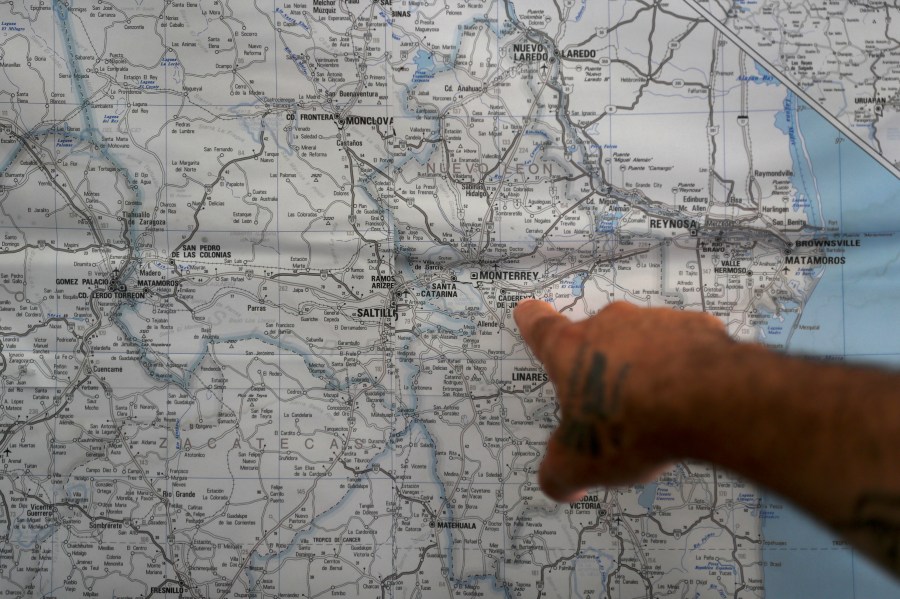 In this Oct. 10, 2019 photo, a Mexican migrant points to a map of U.S.-Mexico border cities, hanging on display at a migrant shelter in Reynosa, Mexico. The Mexican state of Tamaulipas used to be a crossroads. Its dangers are well known. (AP Photo/Fernando Llano)