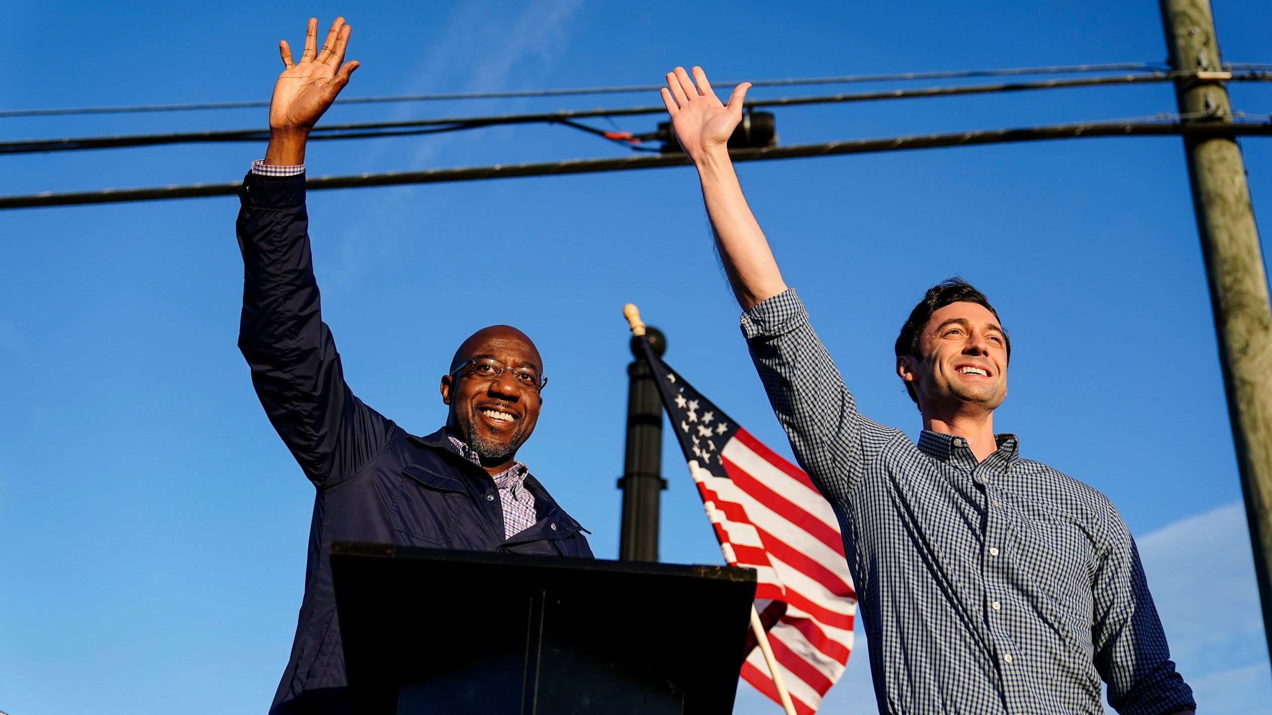 Then Georgia Democratic candidates for U.S. Senate Raphael Warnock, left, and Jon Ossoff, right, gesture toward a crowd during a campaign rally on Nov. 15, 2020, in Marietta, Ga. (Brynn Anderson/Associated Press)