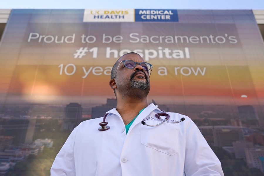 Dr. David Tom Cooke, head of general thoracic surgery at UC Davis Health, poses outside the UC Davis Medical center in Sacramento, Calif., Friday, Dec. 18, 2020. Cooke participated in Pfizer's clinical trial for the coronavirus as part of an effort to reduce skepticism about the vaccine among the Black community. He's now promoting the vaccine's safety and the importance of taking it on his social media pages. (AP Photo/Rich Pedroncelli)