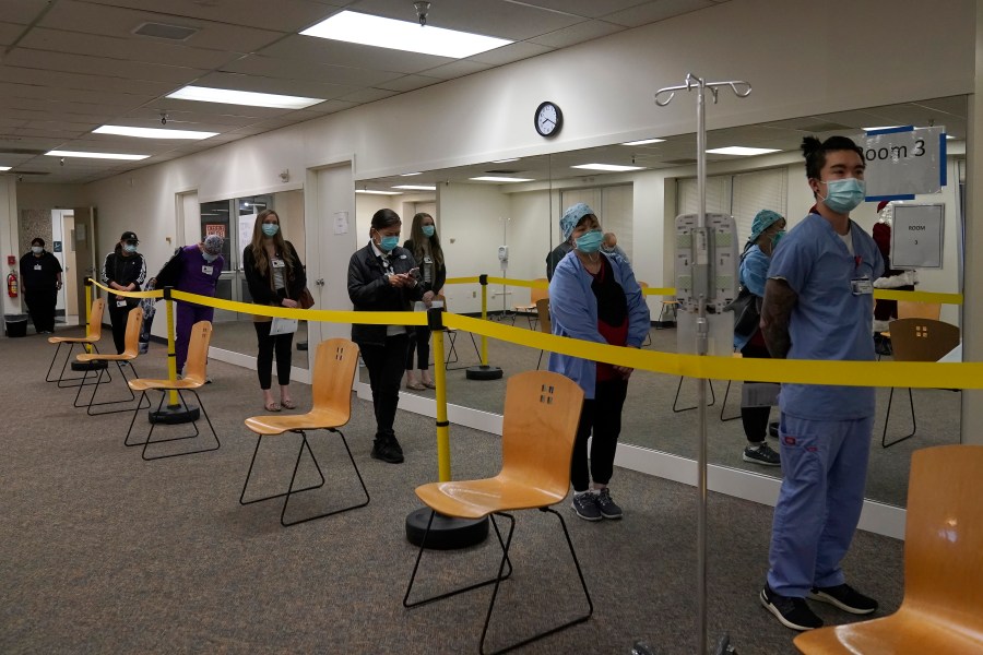 Health care workers wait in line to receive the Pfizer-BioNTech COVID-19 vaccine at Seton Medical Center in Daly City, Calif., Thursday, Dec. 24, 2020. (AP Photo/Jeff Chiu)