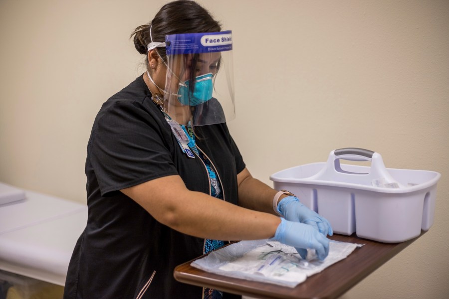 In this Tuesday, Dec. 29, 2020, photo provided by Johns Hopkins Center for American Indian Health, registered nurse Starla Garcia prepares a coronavirus vaccine in Chinle, Ariz., for someone who enrolled in the COVID-19 vaccine trials on the Navajo Nation and initially received a placebo. (Nina Mayer Ritchie/Johns Hopkins Center for American Indian Health via AP)