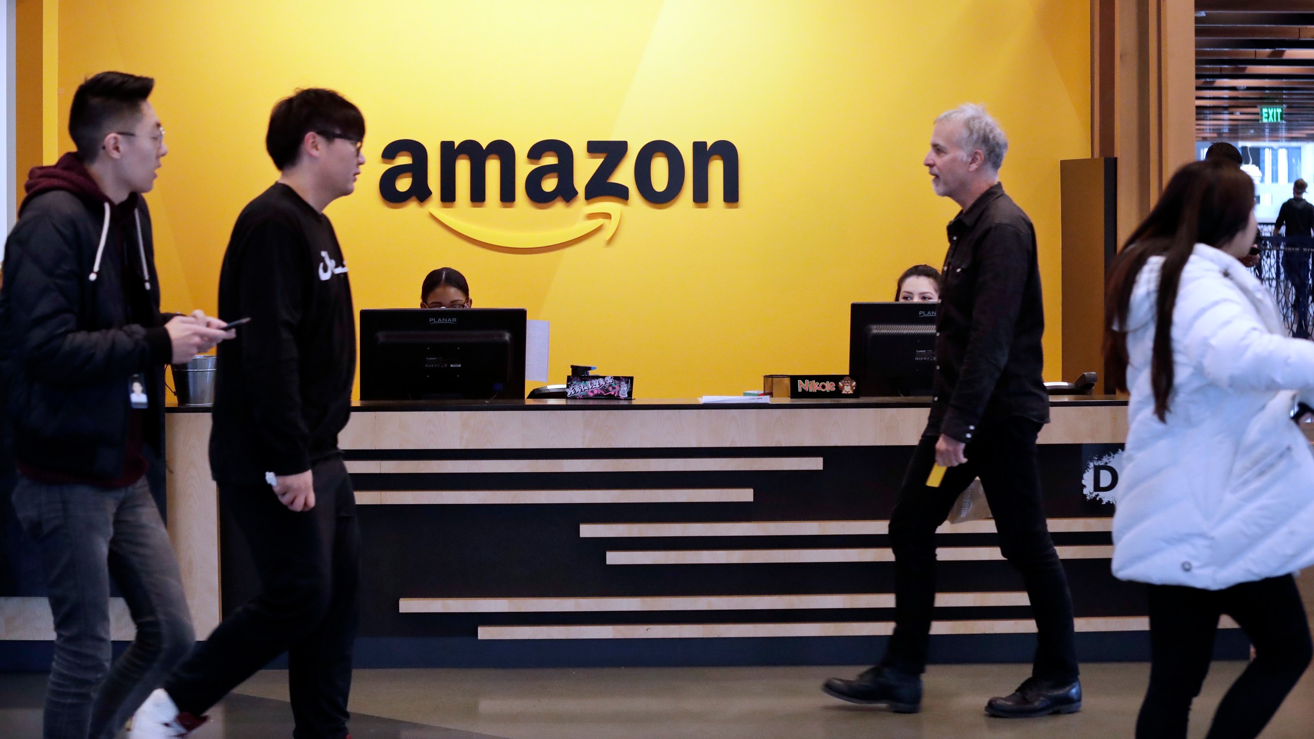 In this Nov. 13, 2018, file photo, employees walk through a lobby at Amazon's headquarters in Seattle. (Elaine Thompson/AP Photo)