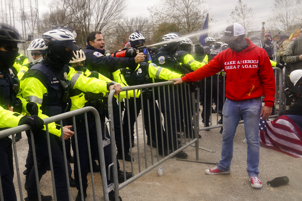 Demonstators loyal to President Donald Trump, are sprayed by police, Wednesday, Jan. 6, 2021, during a day of rioting at the Capitol. (AP Photo/John Minchillo)