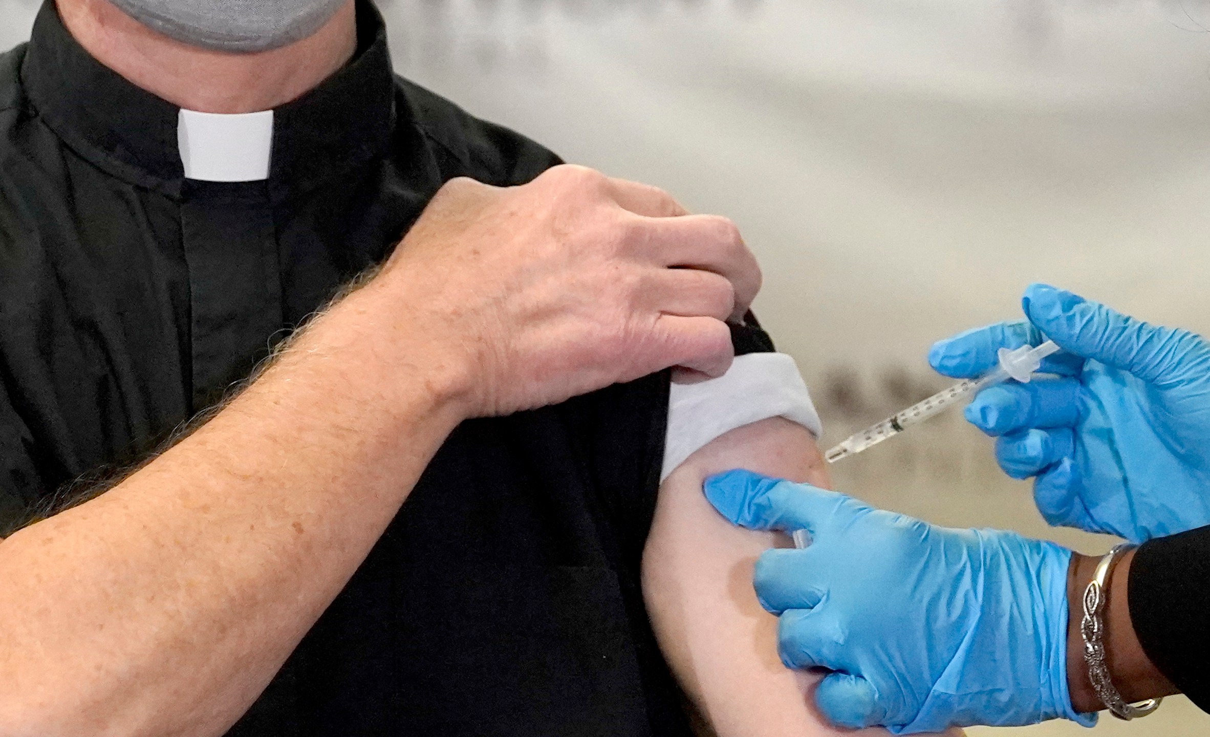 In this Wednesday, Dec. 23, 2020 file photo, a Catholic pastor receives the first of the two Pfizer-BioNTech COVID-19 vaccinations at a hospital in Chicago. (AP Photo/Charles Rex Arbogast)