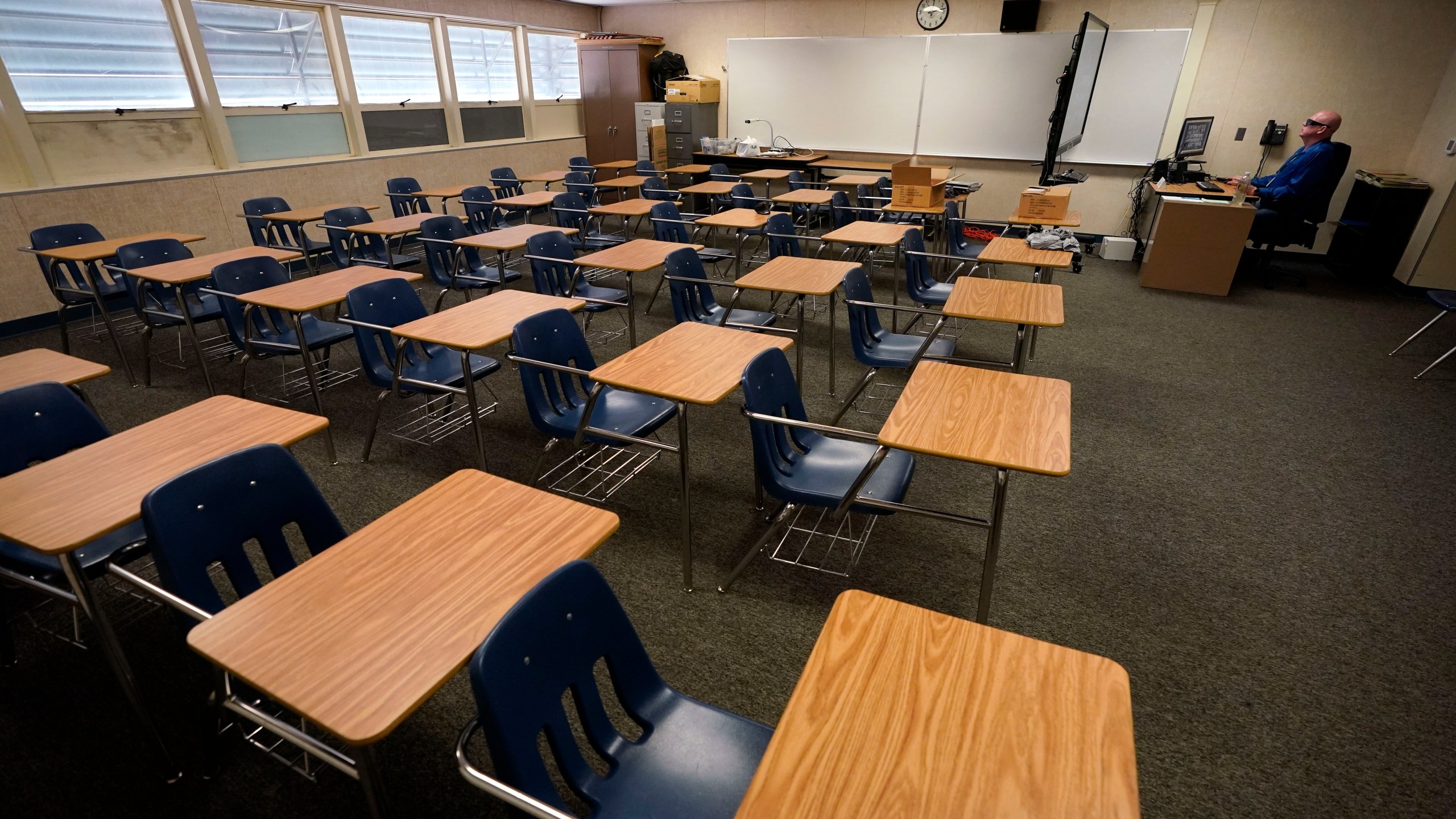 Math teacher Doug Walters sits among empty desks as he takes part in a video conference with other teachers to prepare for at-home learning at Twentynine Palms Junior High School in Twentynine Palms on Aug. 18, 2020. (Gregory Bull / Associated Press)