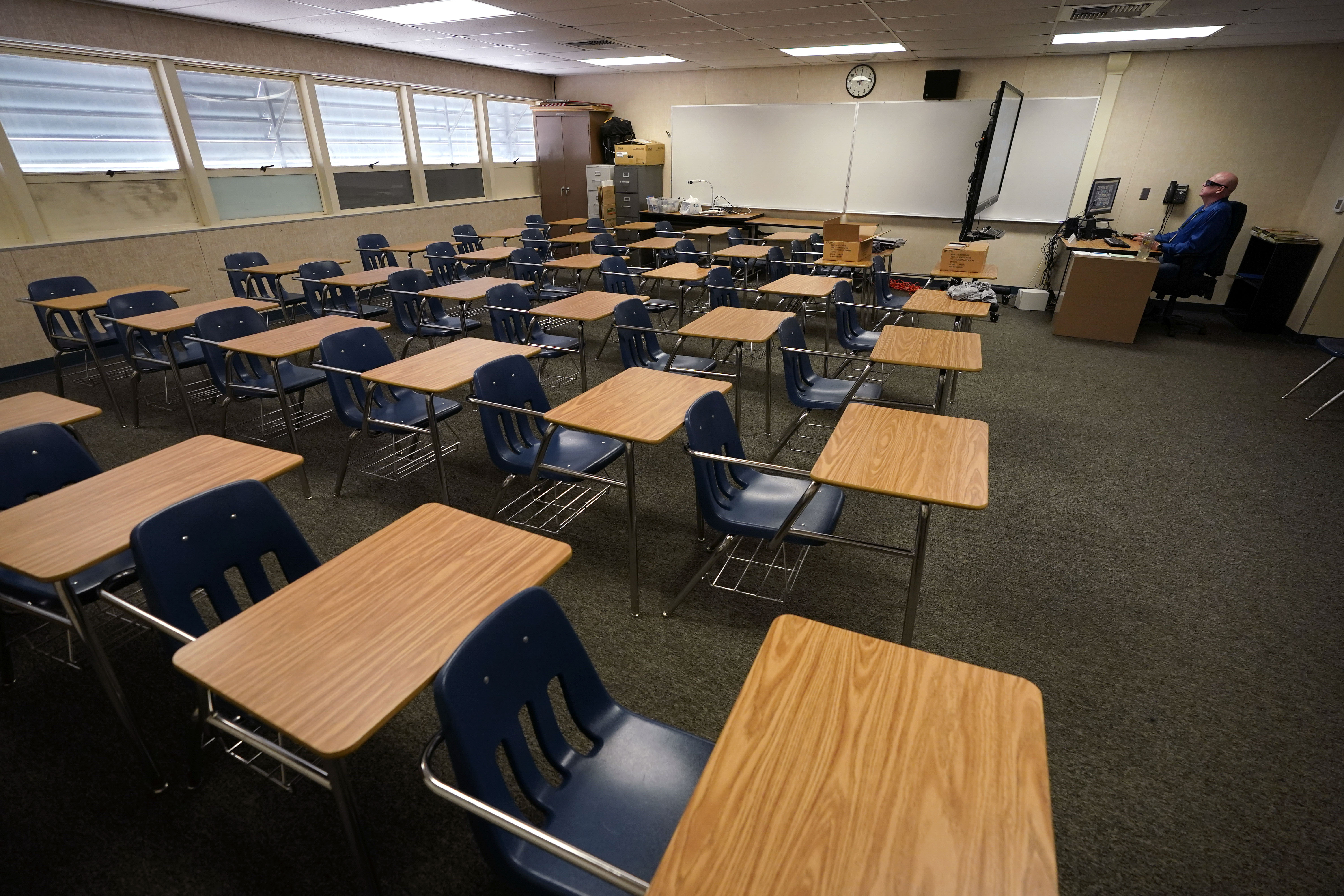 Math teacher Doug Walters sits among empty desks as he takes part in a video conference with other teachers to prepare for at-home learning at Twentynine Palms Junior High School in Twentynine Palms on Aug. 18, 2020. (Gregory Bull / Associated Press)