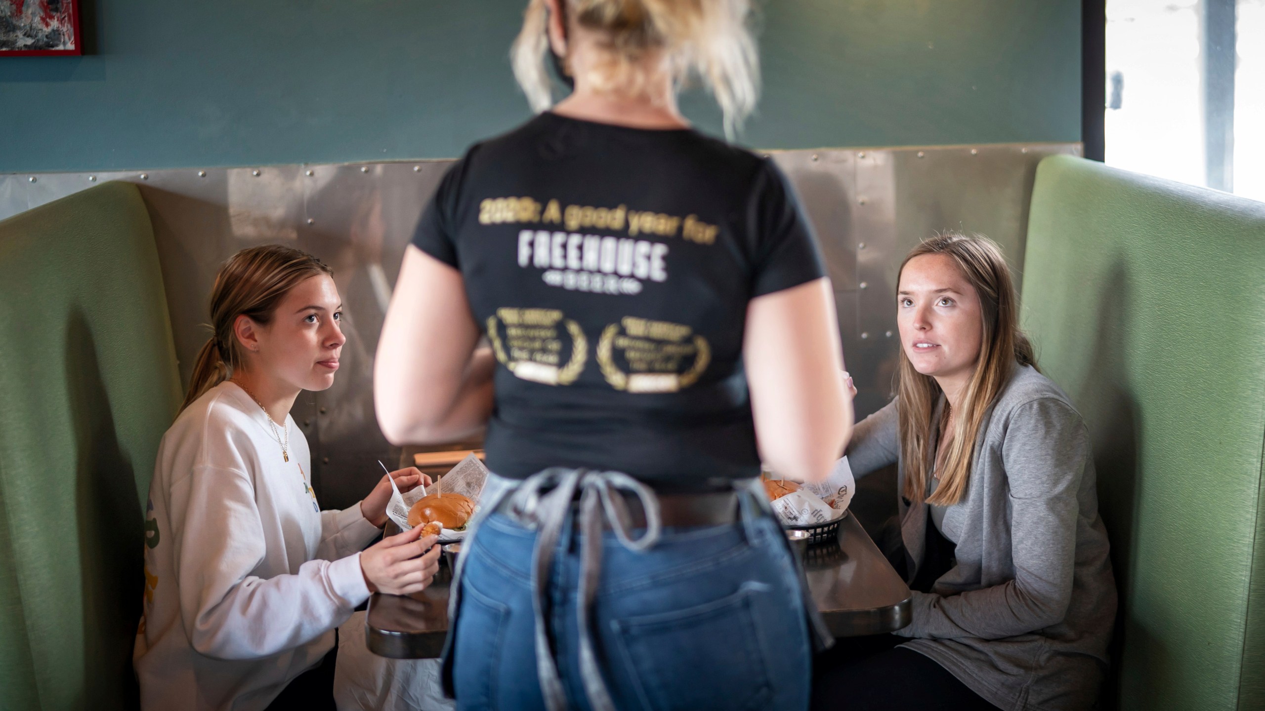 In this Jan. 11, 2021, file photo, Grace Mathre, server at Longfellow Grill, checks on University of St. Thomas students Lundsey Schulz and Maren Daggett in Minneapolis. (Glen Stubbe/Star Tribune via Associated Press)