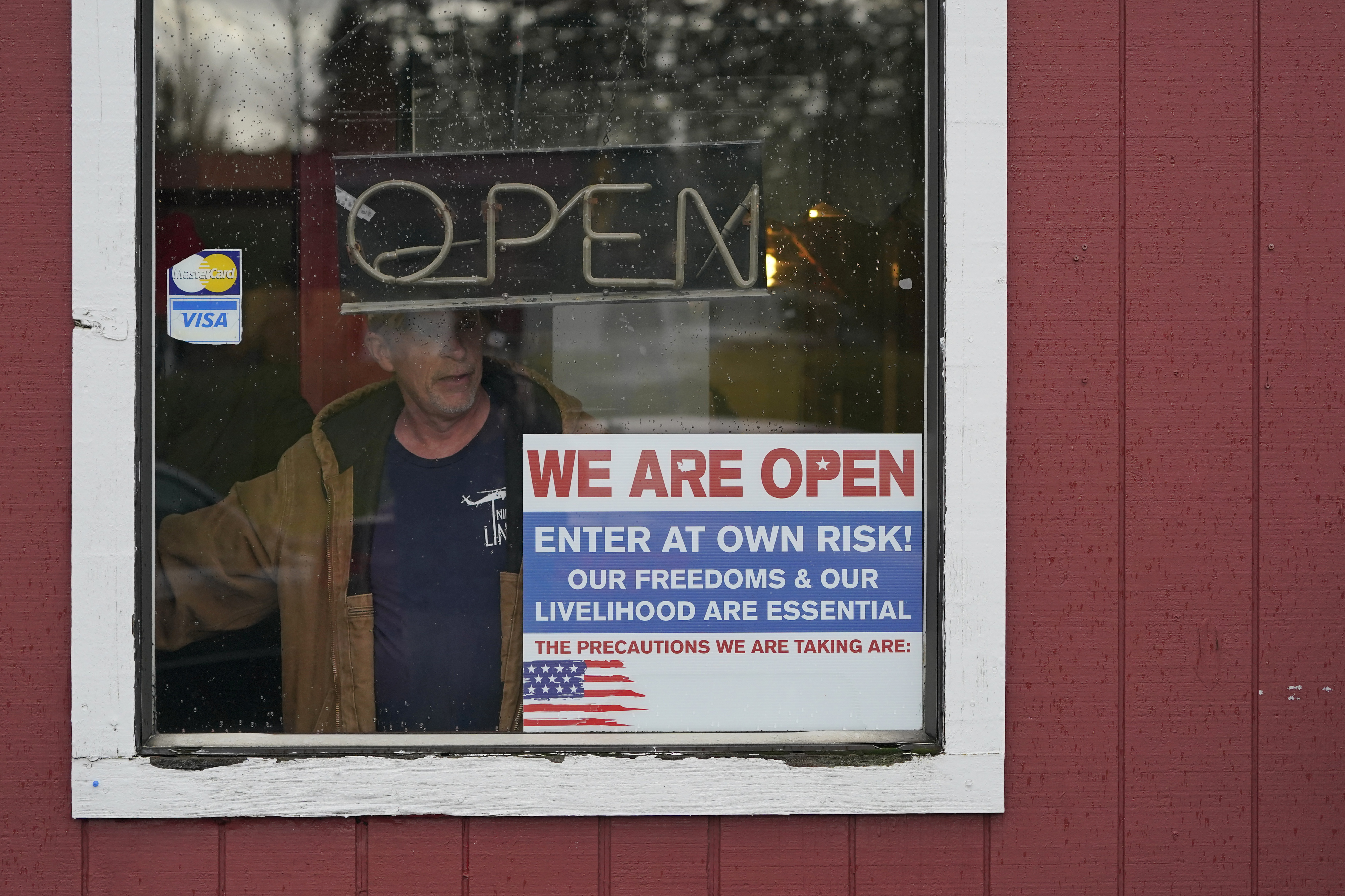 In this Jan. 4, 2021, file photo, a person walks through an entrance to the Farm Boy Drive-In restaurant during a protest rally near Olympia, Wash. The restaurant has been facing fines and penalties for continuing to offer inside dining despite current restrictions on the practice in Washington state due to the coronavirus pandemic. (AP Photo/Ted S. Warren, File)