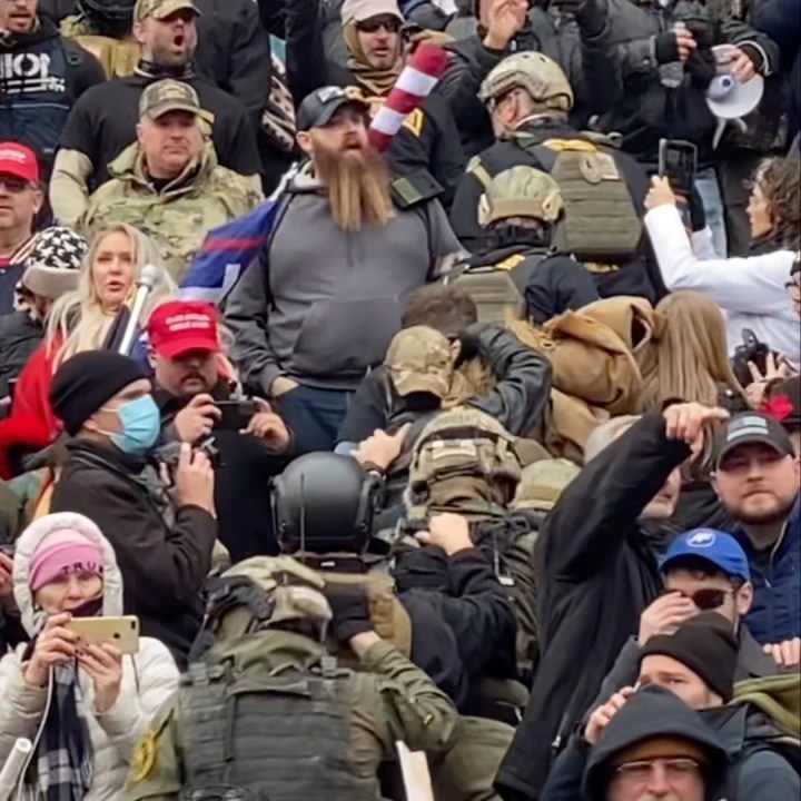 In this Jan. 6, 2021, image from video provided by Robyn Stevens Brody, a line of men wearing helmets and olive drab body armor walk up the marble stairs outside the U.S. Capitol in Washington in an orderly single-file line, each man holding the jacket collar of the man ahead. The formation, known as "Ranger File," is standard operating procedure for a combat team "stacking up" to breach a building. (Robyn Stevens Brody via Associated Press)