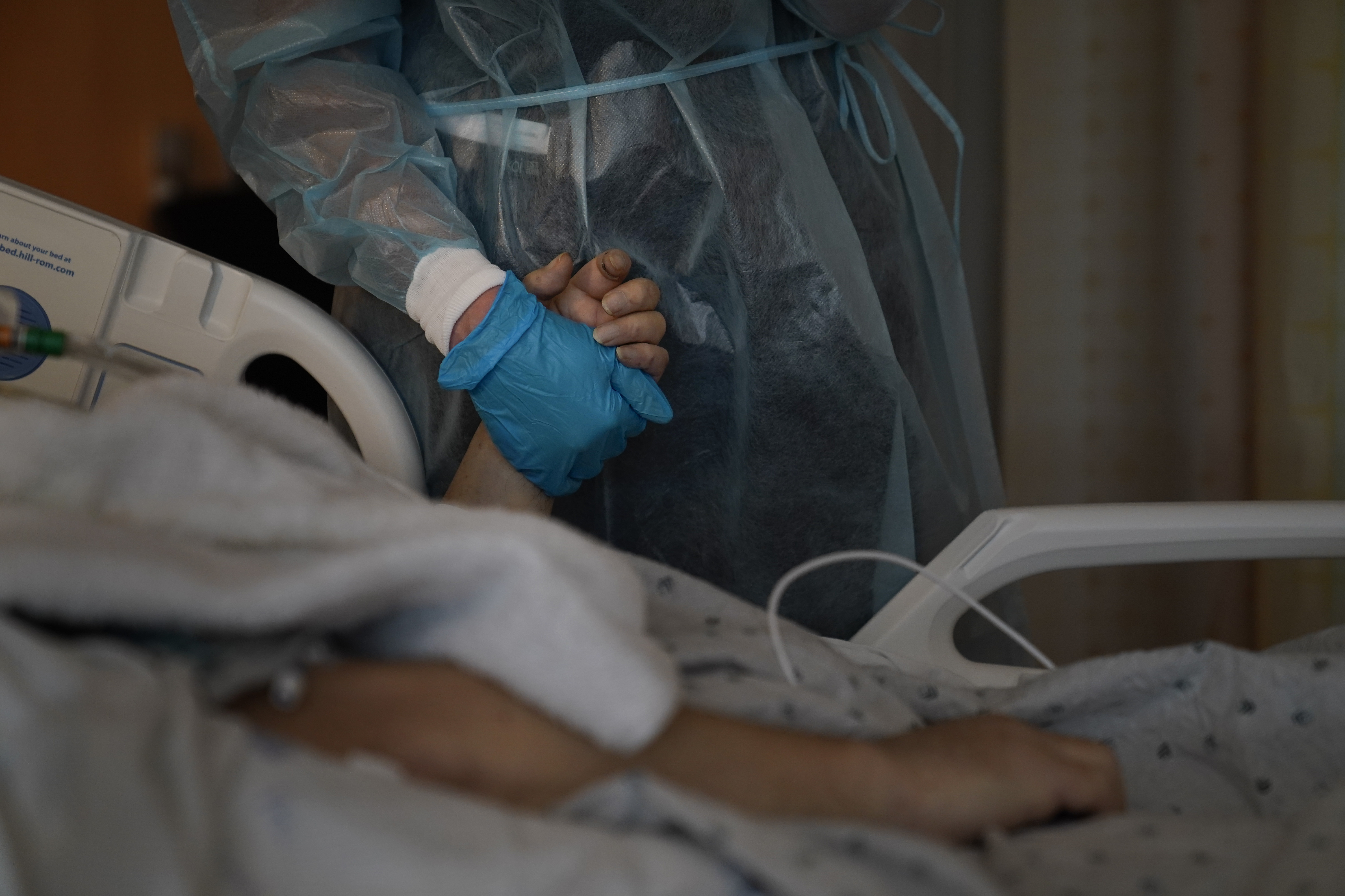 Chaplain Kristin Michealsen holds the hand of a deceased COVID-19 patient while talking on the phone with the patient's family member at Providence Holy Cross Medical Center in the Mission Hills section of Los Angeles on Jan. 9, 2021. (Jae C. Hong / Associated Press)