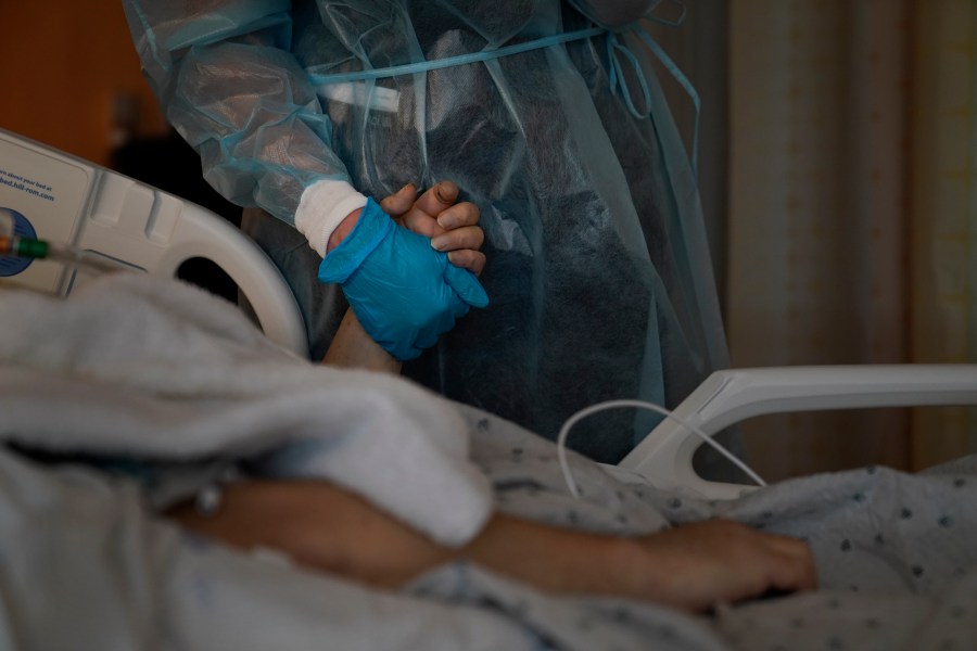 Chaplain Kristin Michealsen holds the hand of a deceased COVID-19 patient while talking on the phone with the patient's family member at Providence Holy Cross Medical Center in the Mission Hills section of Los Angeles on Jan. 9, 2021. (Jae C. Hong / Associated Press)