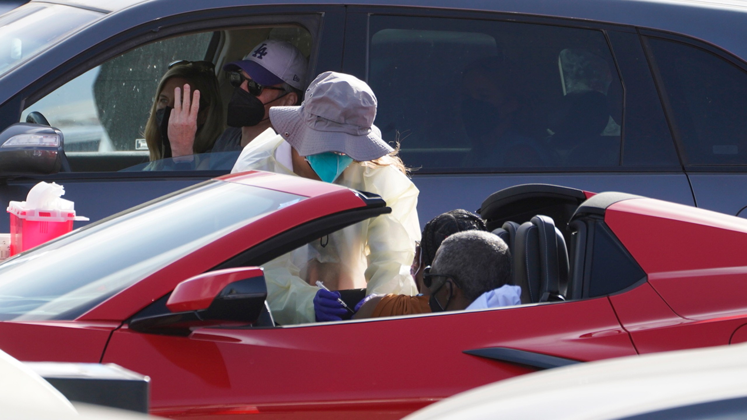 A woman is vaccinated inside a convertible vehicle at a mass COVID-19 vaccination site outside The Forum in Inglewood on Jan. 19, 2021. (Damian Dovarganes / Associated Press)