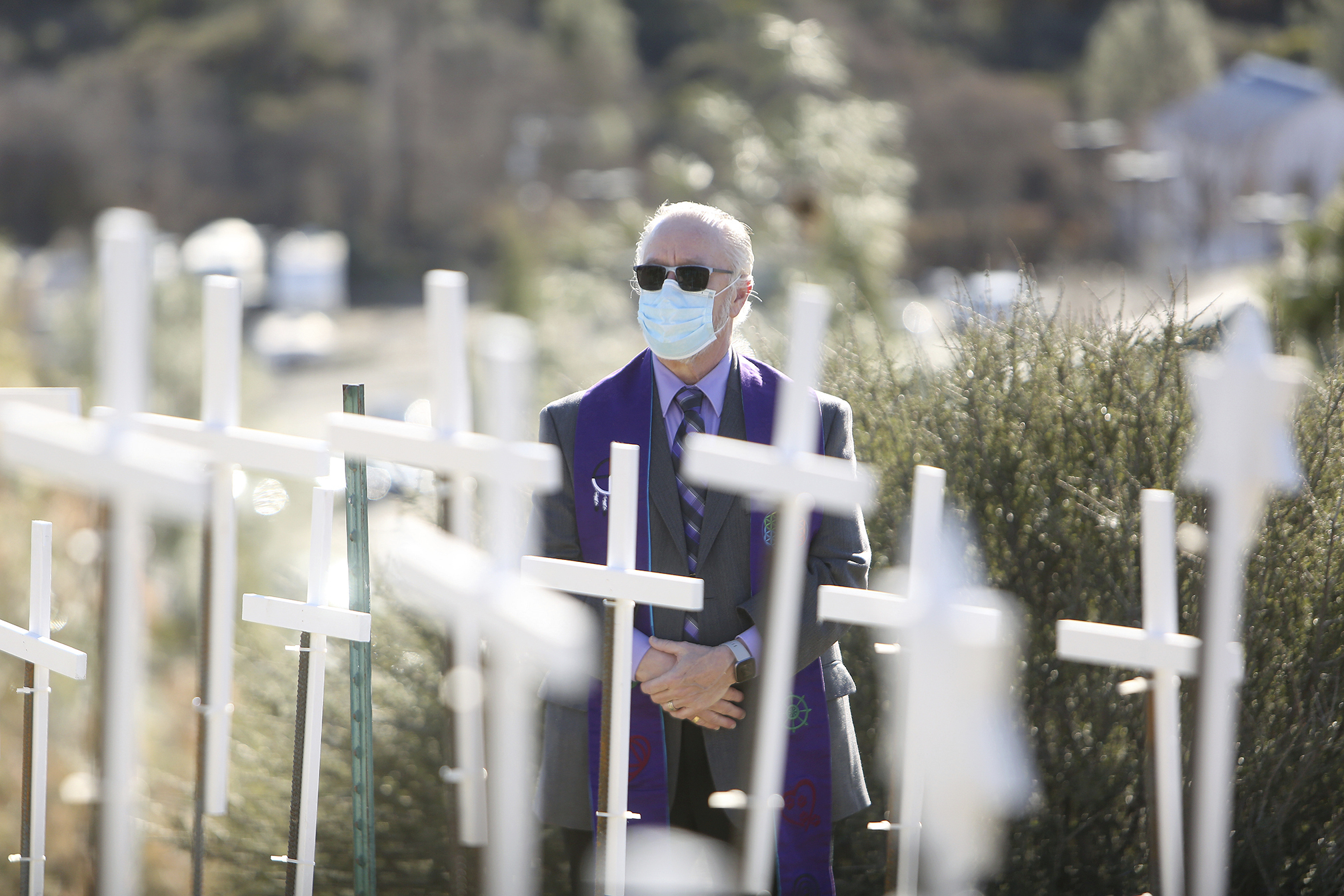 Senior Minister Rev. Rafe Ellis, of Sierra Center for Spiritual Living, gets a close look at the COVID Memorial placed on the Old Barn Self Storage property adjacent to the Golden Center Freeway Tuesday, Jan. 19, 2021 in Grass Valley, Calif. (Elias Funez/The Union via AP)