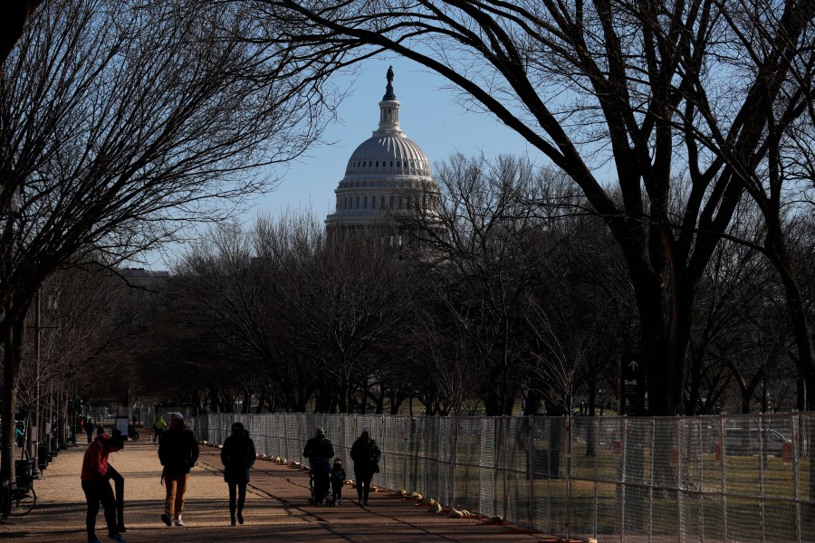 People stroll past a section of the National Mall by the Capitol where workers were still dismantling inauguration installations, after most downtown streets and public spaces had reopened to the public, on Saturday, Jan. 23, 2021 in Washington. (AP Photo/Rebecca Blackwell)