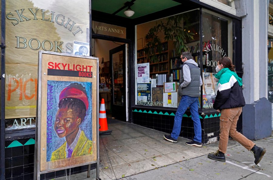 Eric and Tess from Pasadena, Calif., enter the Skylight Book store, decorated with a poster of American poet Amanda Gorman, in Los Feliz neighborhood of Los Angeles Monday, Jan. 25, 2021. (AP Photo/Damian Dovarganes)