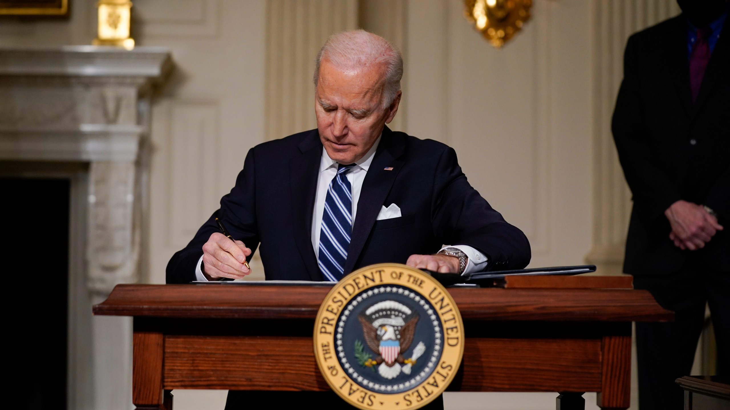 President Joe Biden signs an executive order on climate change in the State Dining Room of the White House on Jan. 27, 2021. (Evan Vucci / Associated Press)