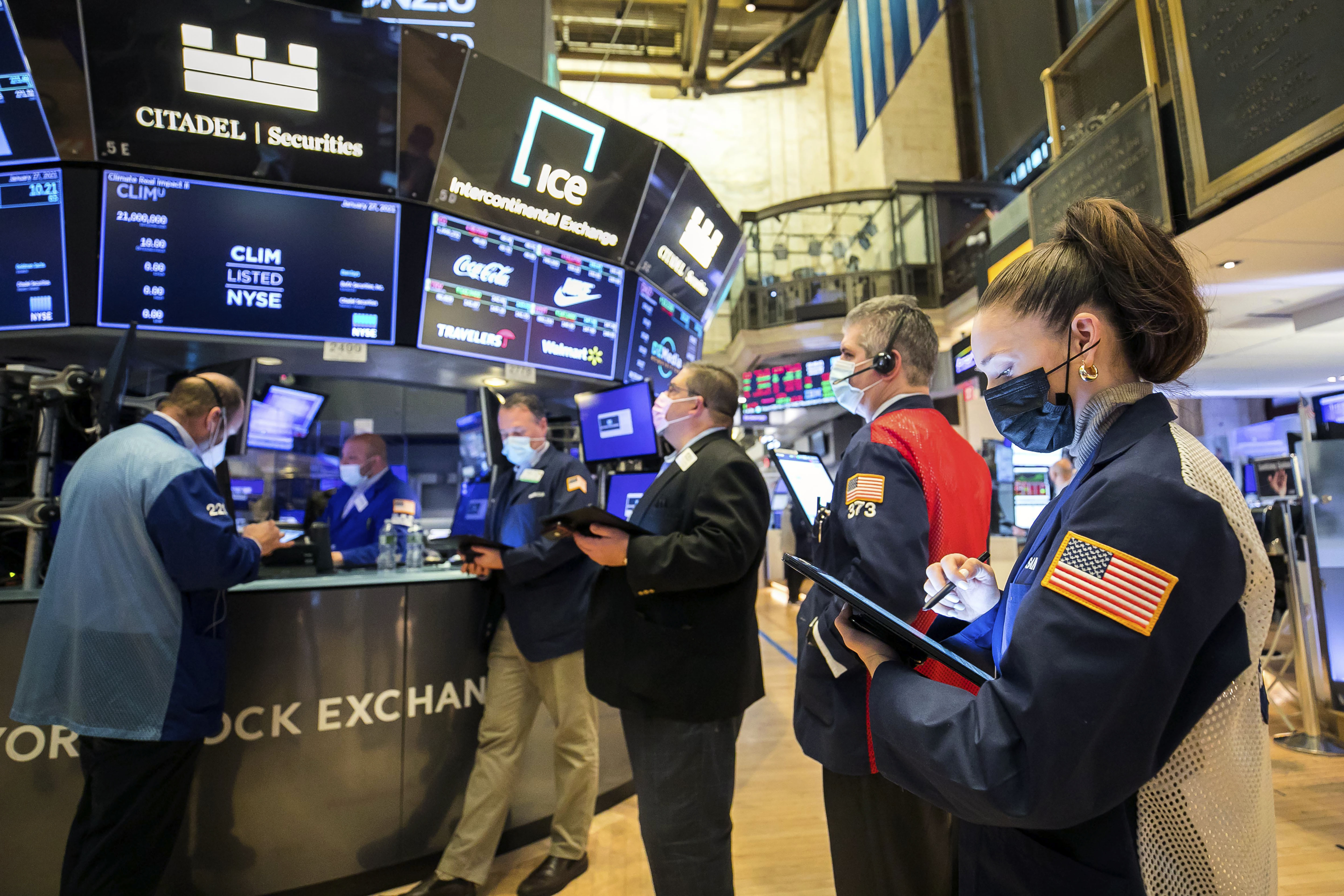 In this photo provided by the New York Stock Exchange, trader Samantha Tavares, right, works with colleagues on the floor, Wednesday, Jan. 27, 2021. Stocks were broadly lower in afternoon trading Wednesday, as investors focus on the outlook for the economy and corporate profits amid a still-raging coronavirus pandemic. (Courtney Crow/New York Stock Exchange via AP)