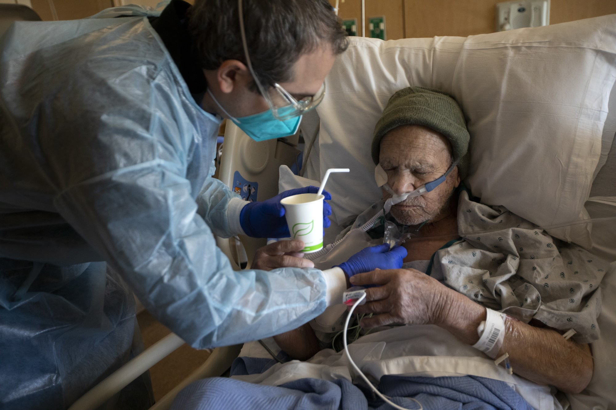 Chaplain Kevin Deegan, left, gives Juan Legaspi-Lozano, 90, a small sip of water in the COVID unit the week of Dec. 27, 2020 at Providence Holy Cross Medical Center in Mission Hills, Calif. It is one of several Southern California hospitals struggling with a crush of severely sick patients.(Francine Orr / Los Angeles Times)