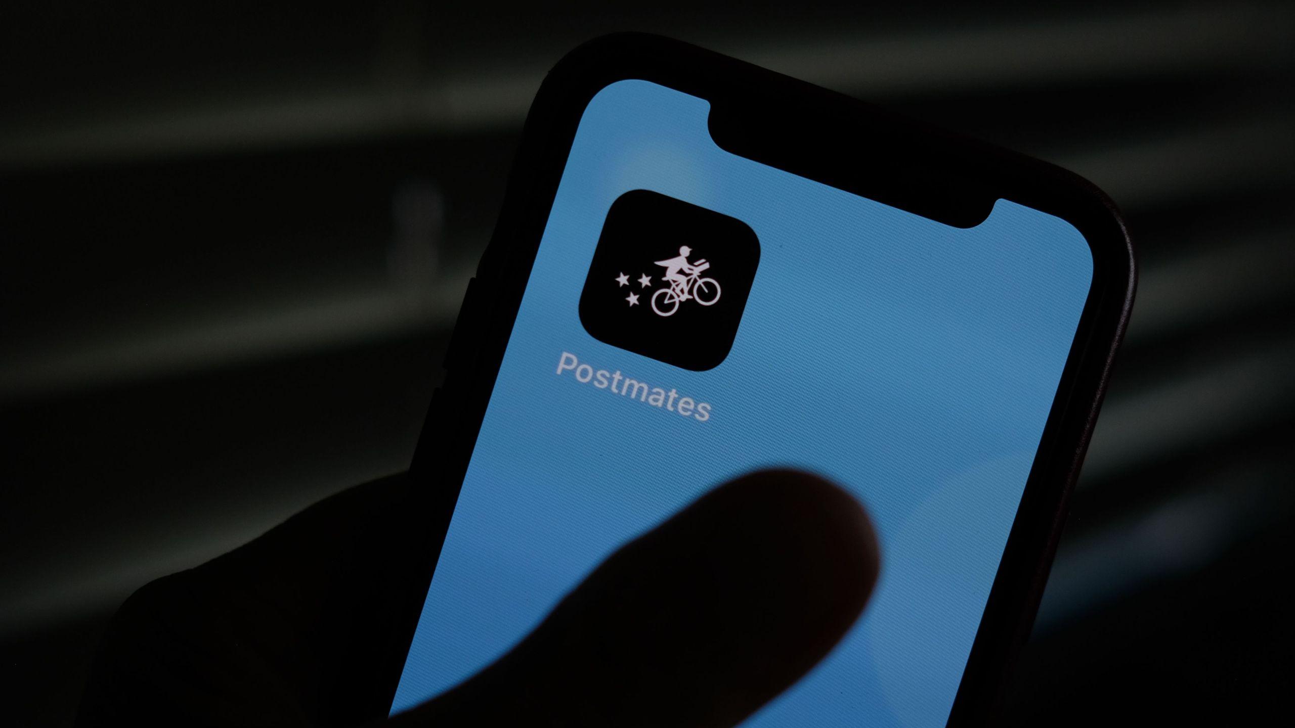 This illustration photo taken on June 30, 2020, shows the logo of delivery app Postmates on a smartphone screen in Los Angeles. (Chris Delmas / AFP / Getty Images)