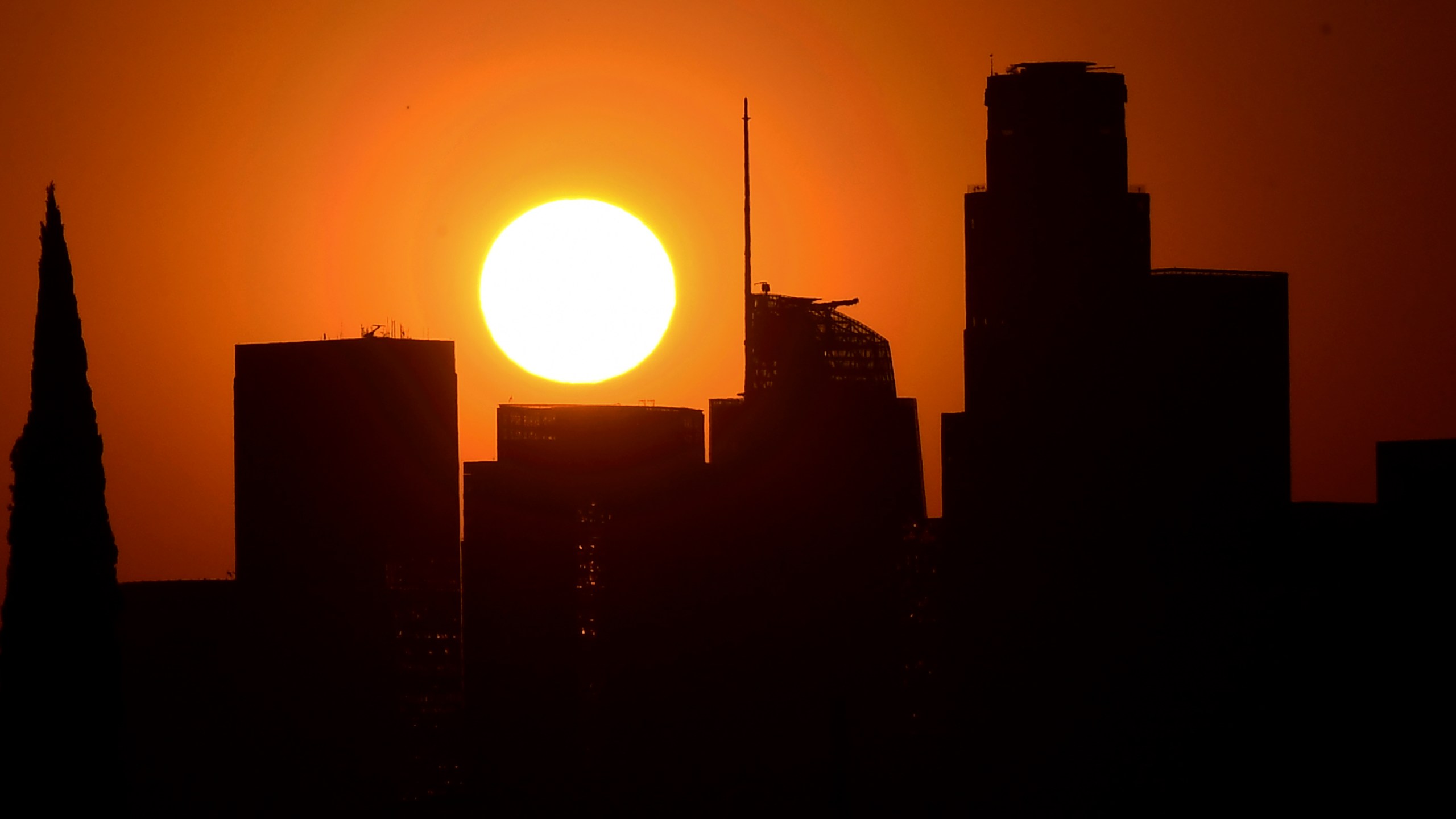 The sun sets behind highrise buildings in downtown Los Angeles on Sept. 30, 2020. (Frederic J. Brown / AFP / Getty Images)