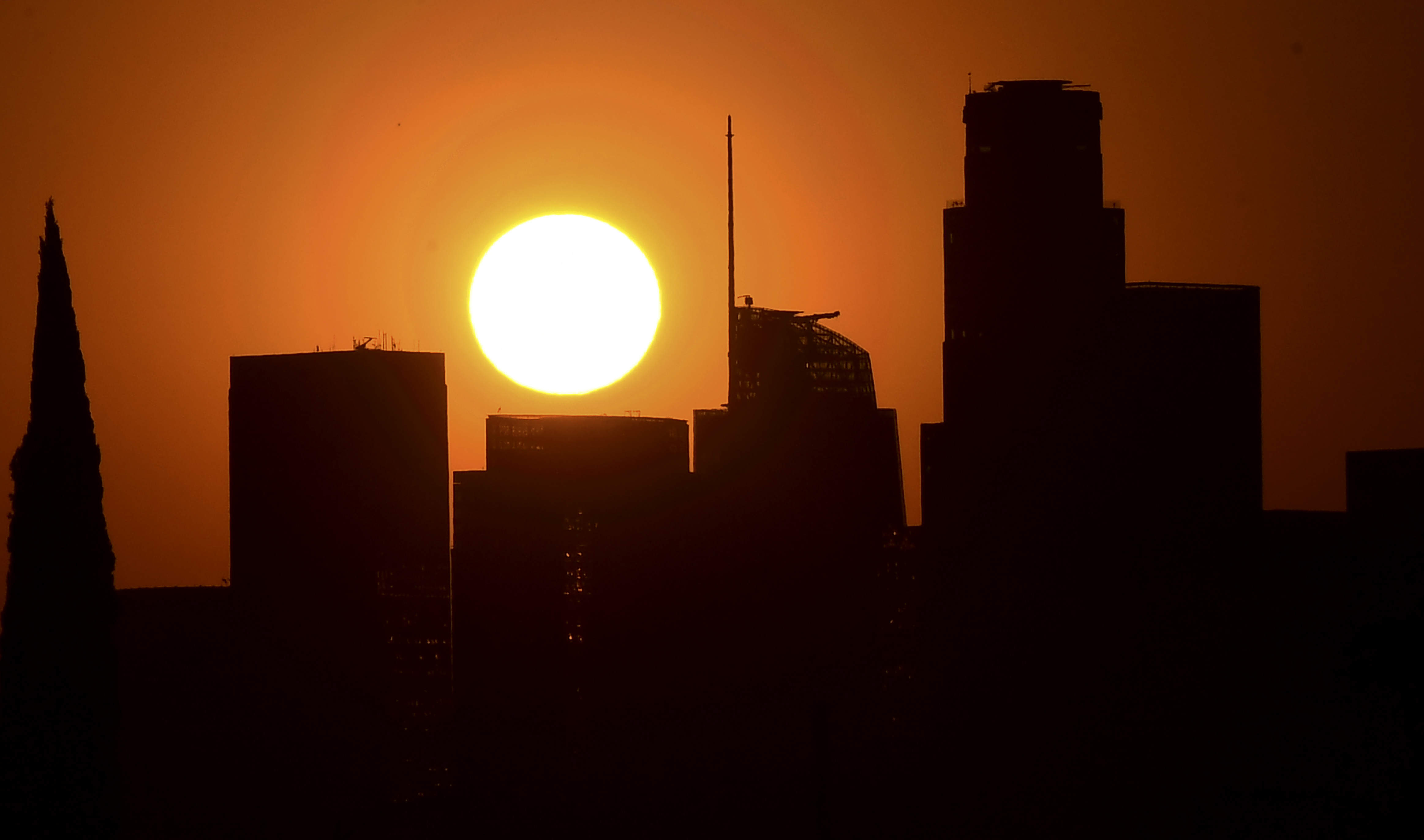 The sun sets behind highrise buildings in downtown Los Angeles on Sept. 30, 2020. (Frederic J. Brown / AFP / Getty Images)