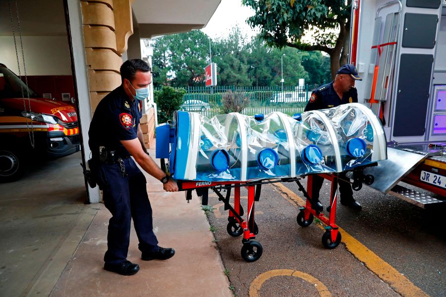 City of Tshwane's Special Infection Unit Leading Emergency Care practitioners push the isolation chamber equipped with a negative pressure filtration system used to transport positive COVID-19 patients before starting their night shift at the Hatfield Emergency Station, in Pretoria, on Dec. 28, 2020. ((PHILL MAGAKOE/AFP via Getty Images)