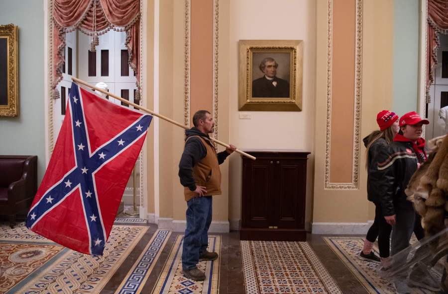 A supporter of Donald Trump holds a Confederate flag outside the Senate Chamber during a protest after breaching the US Capitol in Washington, D.C., Jan. 6, 2021. (SAUL LOEB/AFP via Getty Images)