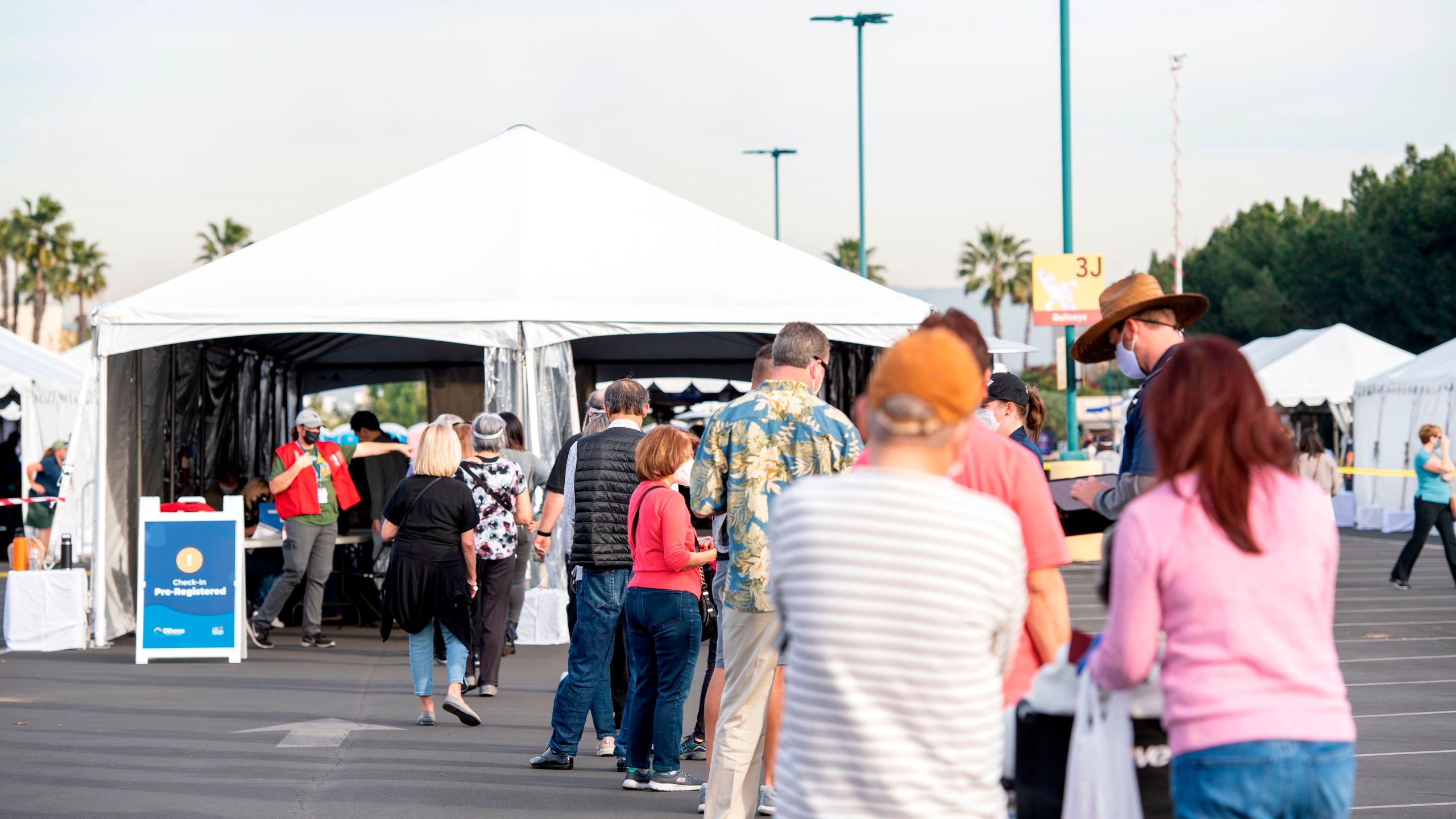 People wait in line in a Disneyland parking lot to receive COVID-19 vaccines on the opening day of the Disneyland vaccination "super Point-of-Dispensing" (POD) site on Jan. 13, 2021, in Anaheim, California. (VALERIE MACON/AFP via Getty Images)