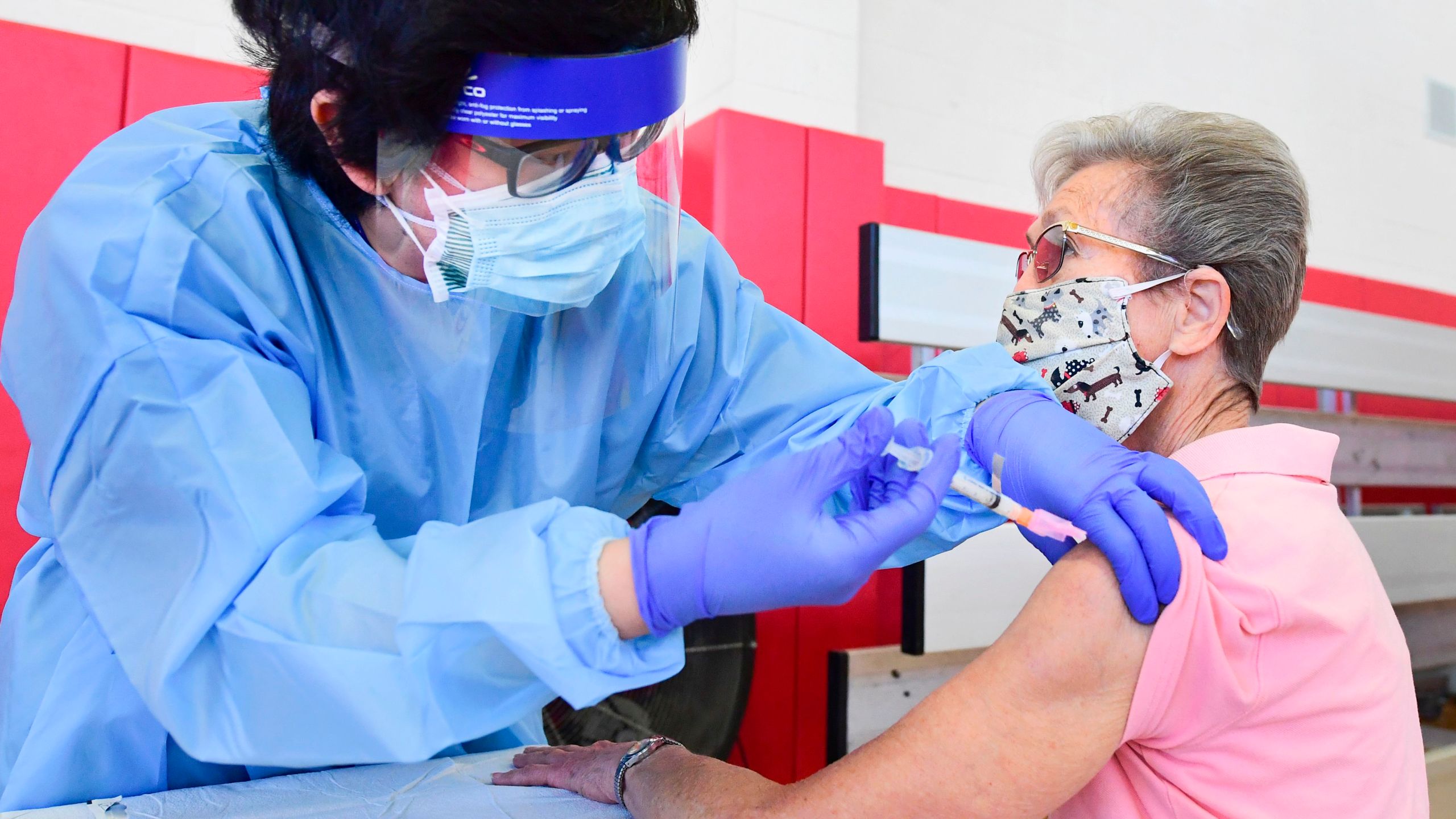 Registered nurse Kevin Salgado administers the COVID-19 vaccine into the arm of Arline Allman, 86, at the Corona High School gymnasium in Corona in Riverside County, on Jan. 15, 202. (FREDERIC J. BROWN/AFP via Getty Images)