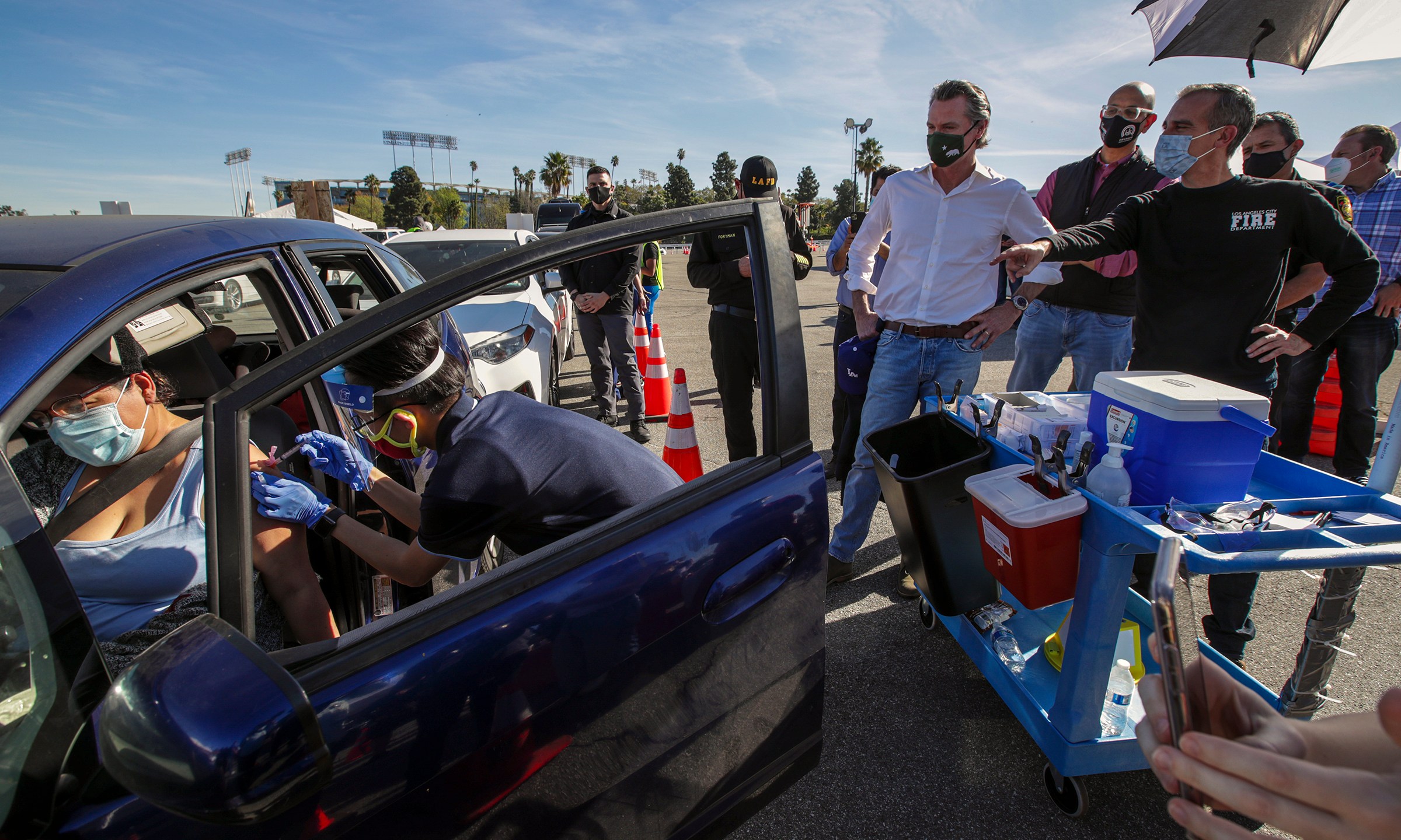 Los Angeles Mayor Eric Garcetti, at right, and California Governor Gavin Newsom, center, tour the mass COVID-19 vaccination site at Dodger Stadium on Jan. 15, 2021. (Irfan Khan / AFP / Getty Images)