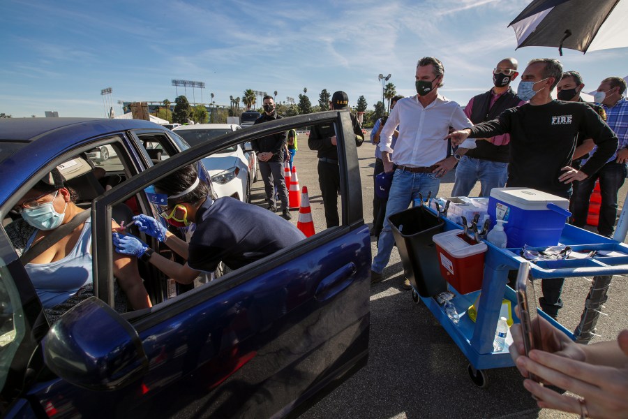 Los Angeles Mayor Eric Garcetti, at right, and California Governor Gavin Newsom, center, tour the mass COVID-19 vaccination site at Dodger Stadium on Jan. 15, 2021. (Irfan Khan / AFP / Getty Images)