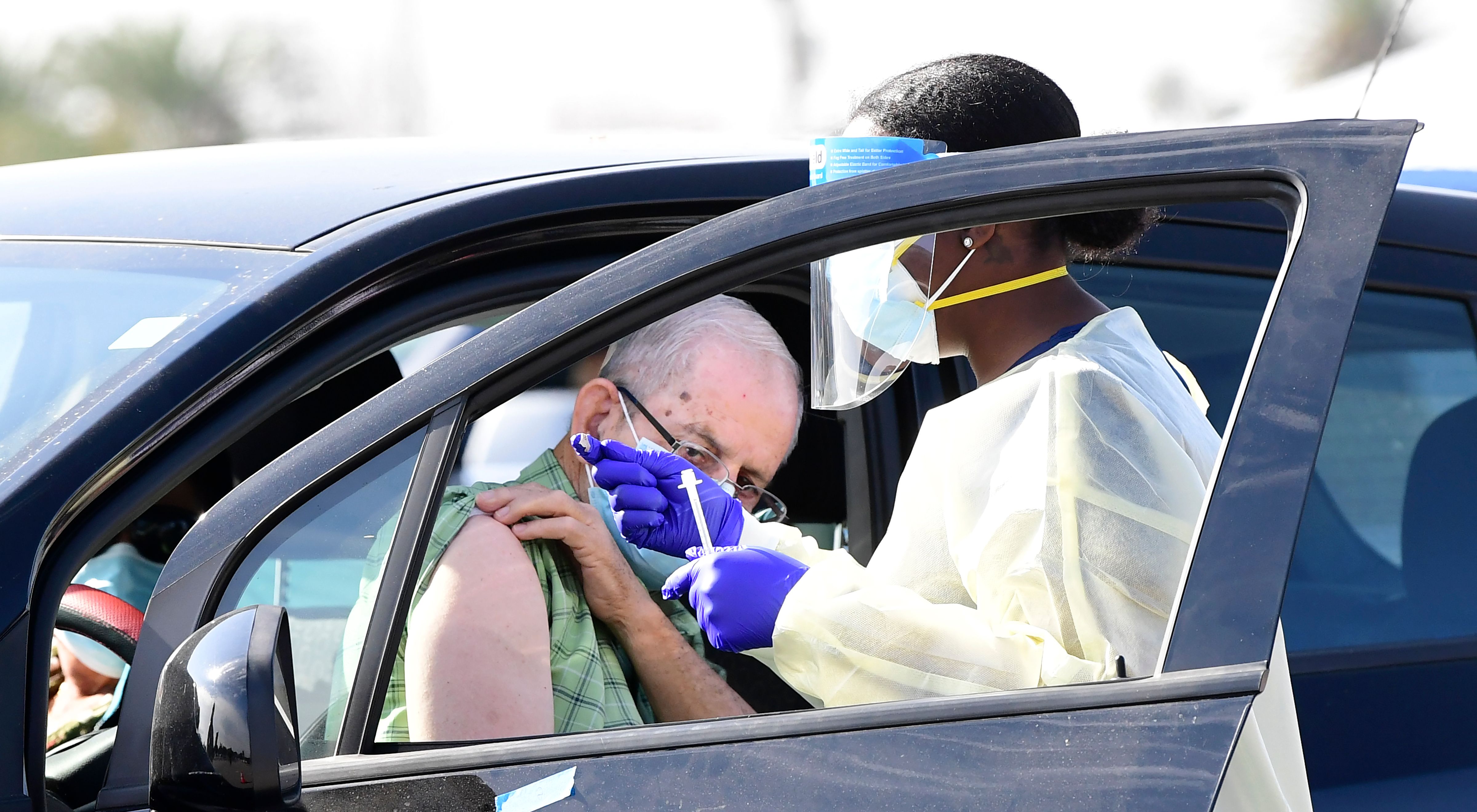 People pull up in their vehicles for Covid-19 vaccines in the parking lot of The Forum in Inglewood on Jan. 19, 2021. (FREDERIC J. BROWN/AFP via Getty Images)