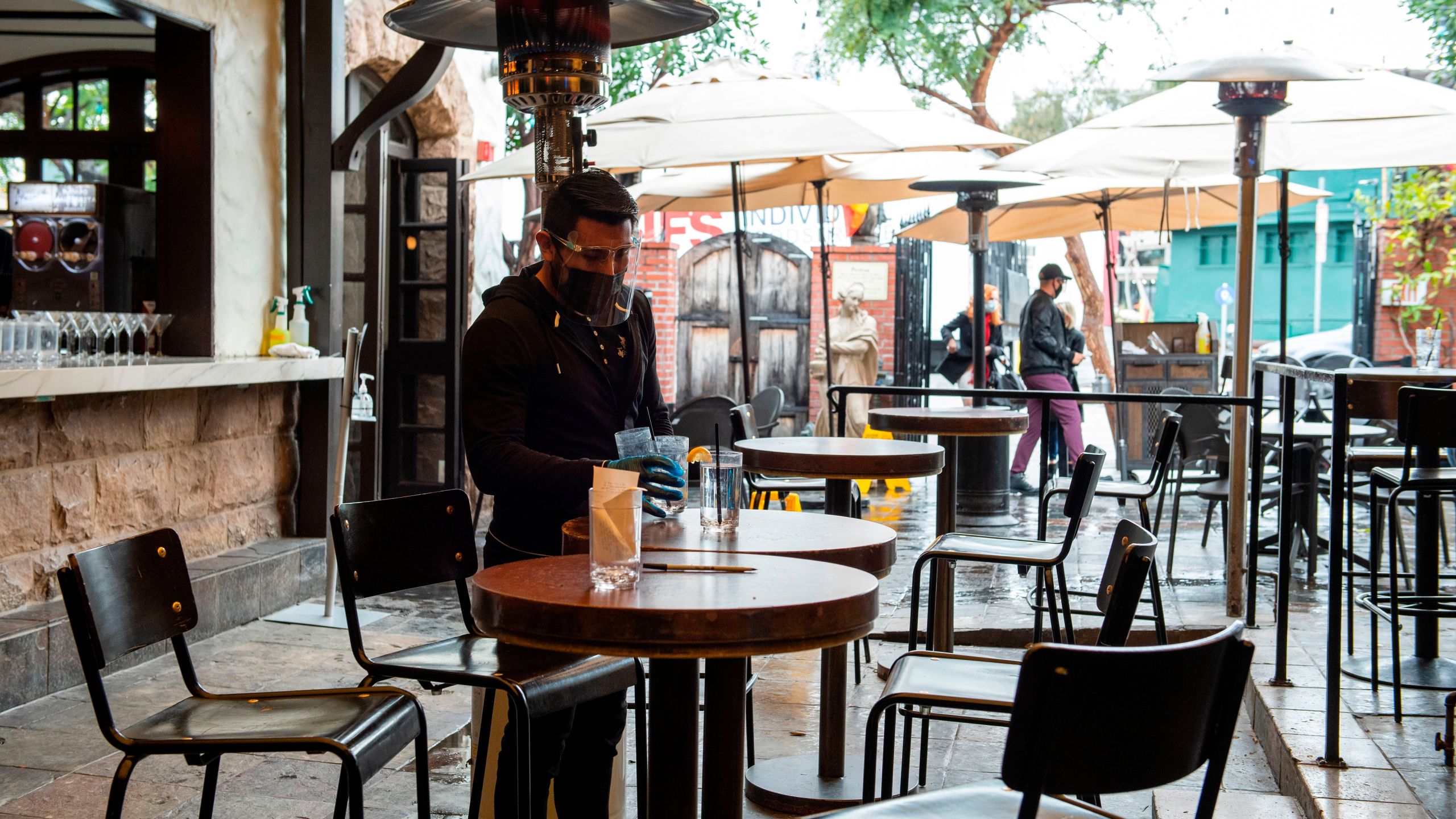 An employee sanitizes the tables of The Abbey Food & Bar outdoor seating area on January 29, 2021 in West Hollywood, California. (VALERIE MACON/AFP via Getty Images)