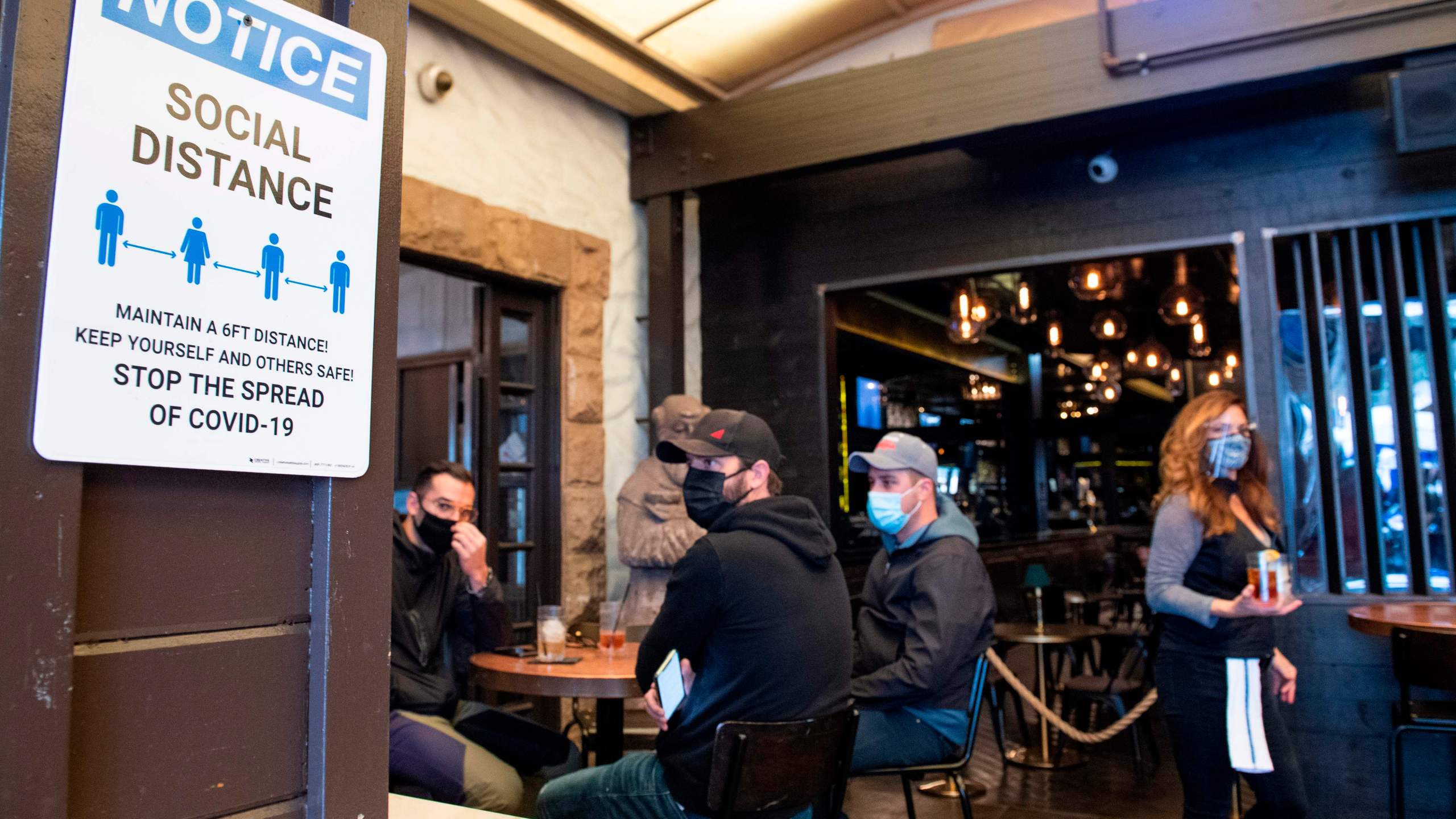 A notice inviting patrons to social distance is seen in the outdoor seating area of The Abbey Food & Bar on January 29, 2021, in West Hollywood, California. (Valerie Macon/AFP via Getty Images)