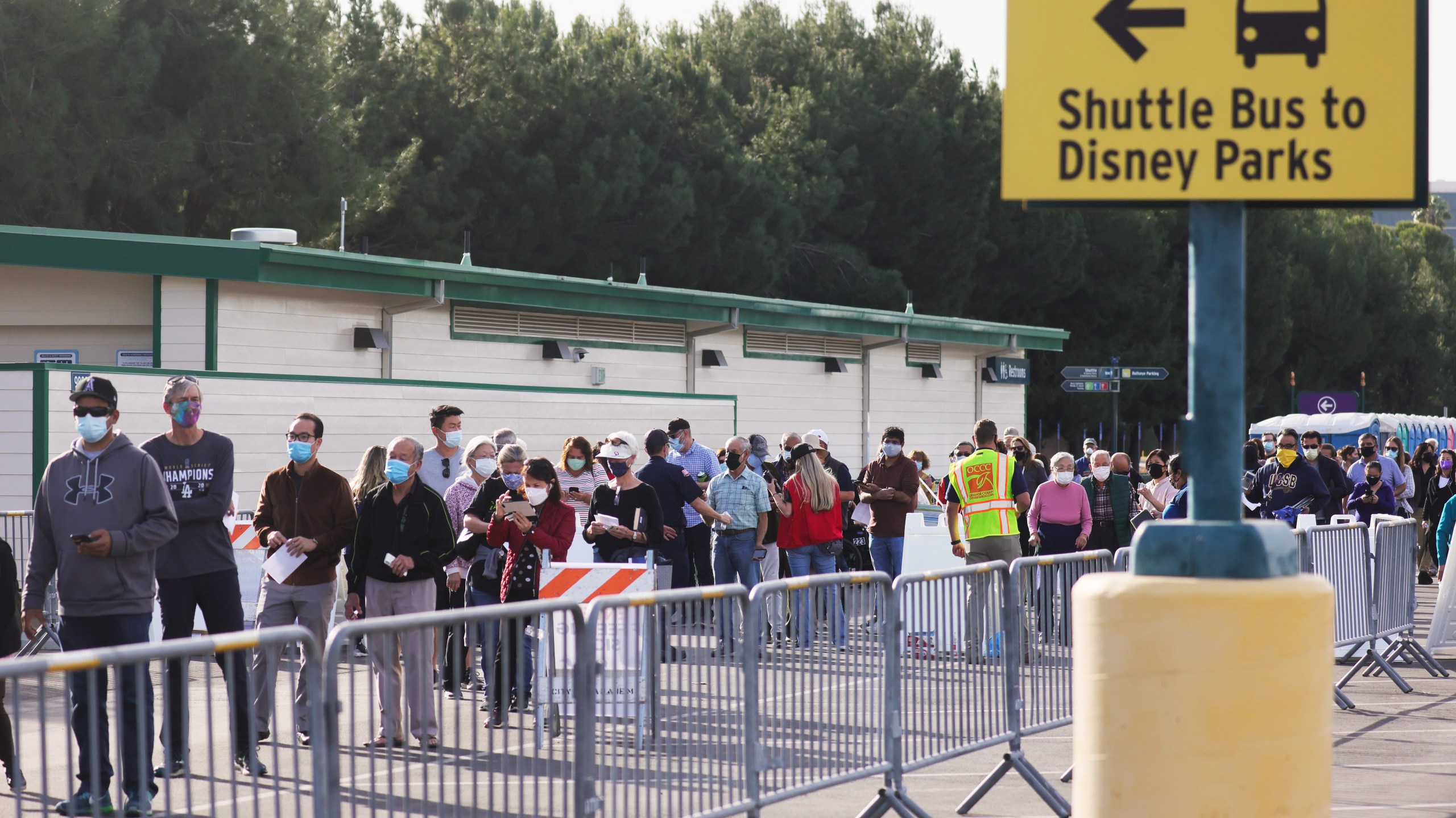 People wait in line to receive the COVID-19 vaccine at a mass vaccination site in a parking lot for Disneyland Resort on January 13, 2021 in Anaheim, California. (Photo by Mario Tama/Getty Images)