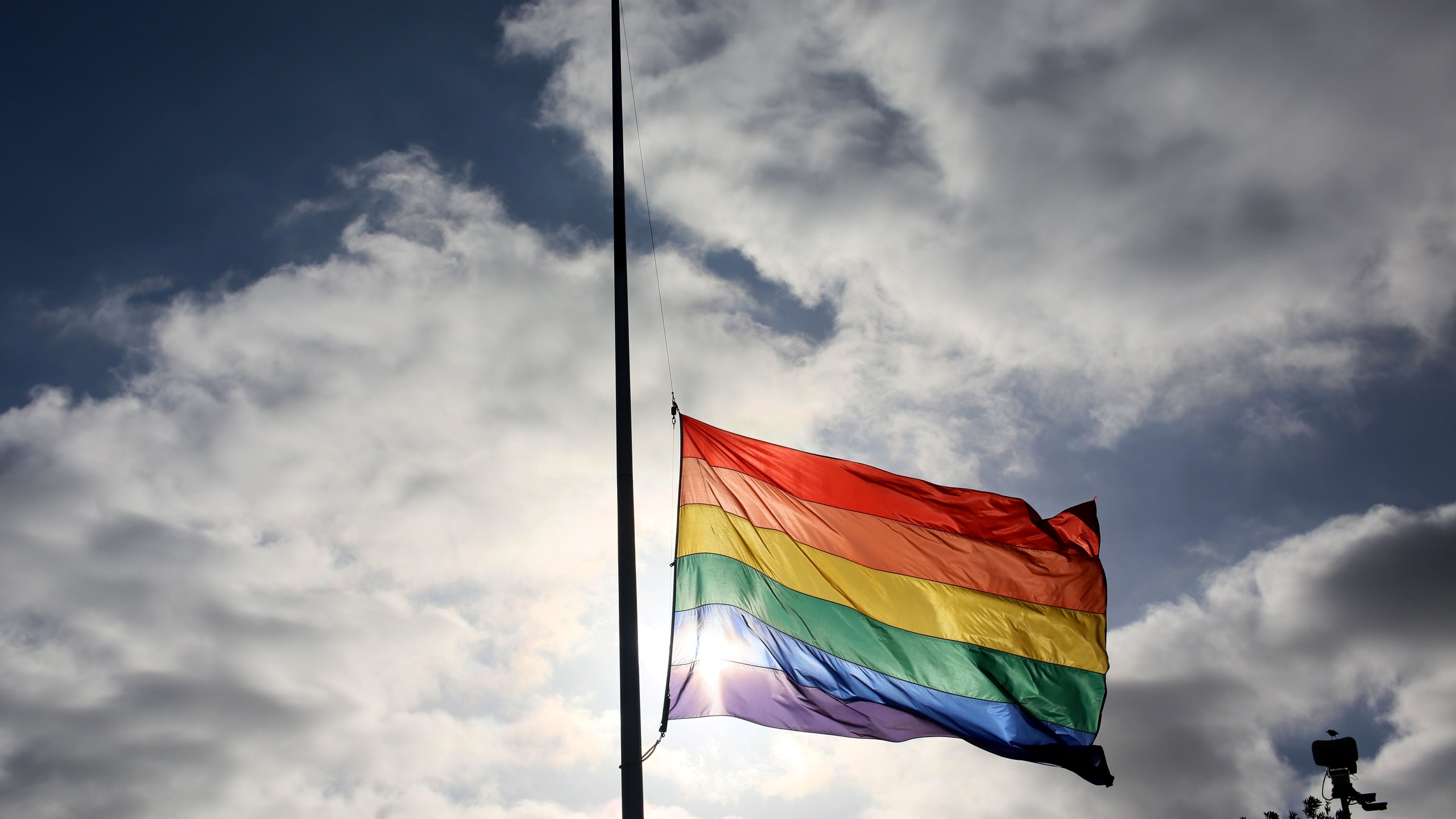 A pride flag stands a half mast during a memorial service in San Diego, California on June 12, 2016, for the victims of the Orlando Nighclub shooting.(Sandy Huffaker/AFP via Getty Images)