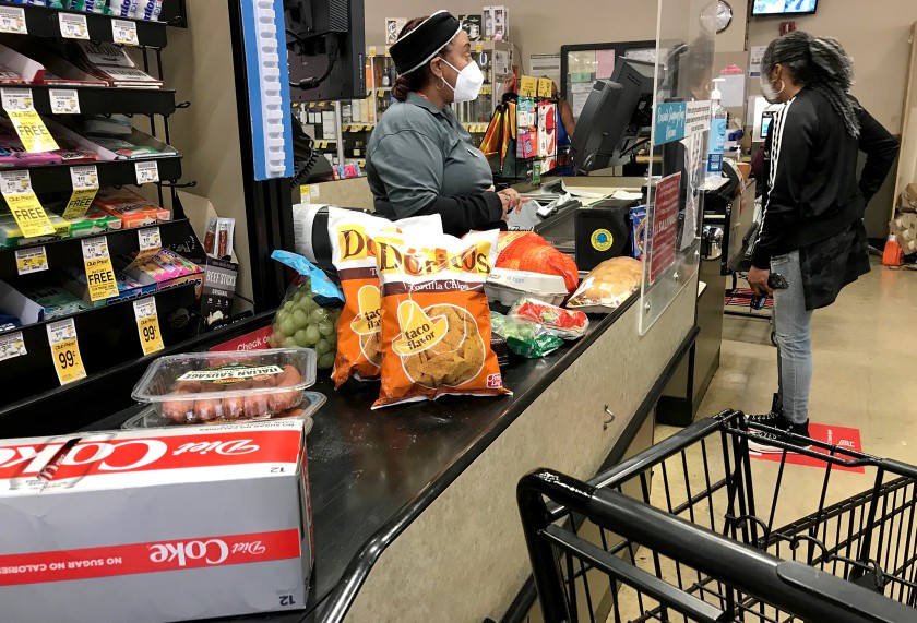 A cashier helps a customer at the checkout stand in the Von’s grocery store in Long Beach on Dec. 16, 2020. (Los Angeles Times)