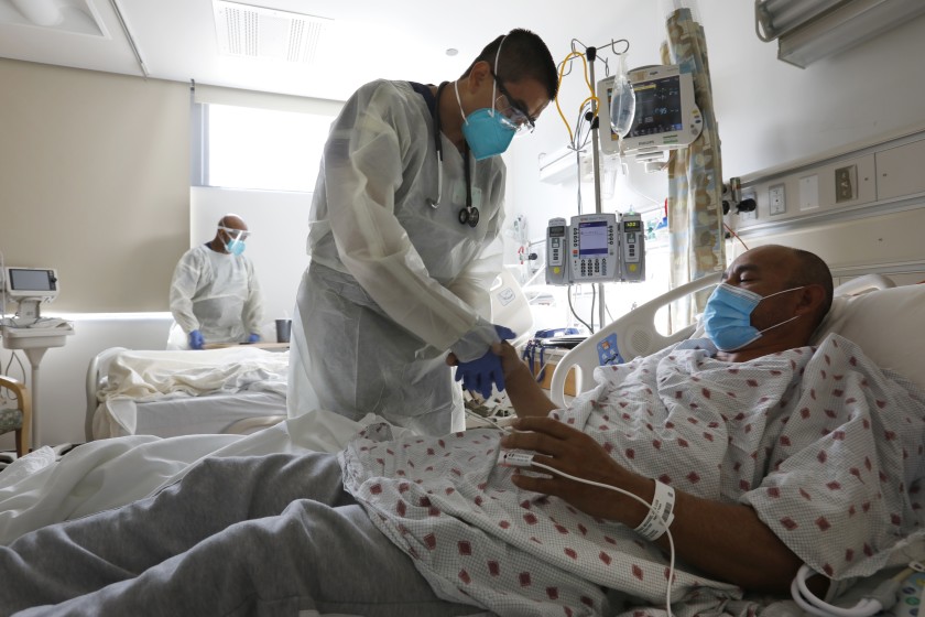 Dr. Jeison Recinos checks on COVID-19 patient Jose Luis Andrade Moscoso at Olive View-UCLA Medical Center on Jan. 11, 2021. (Carolyn Cole / Los Angeles Times)